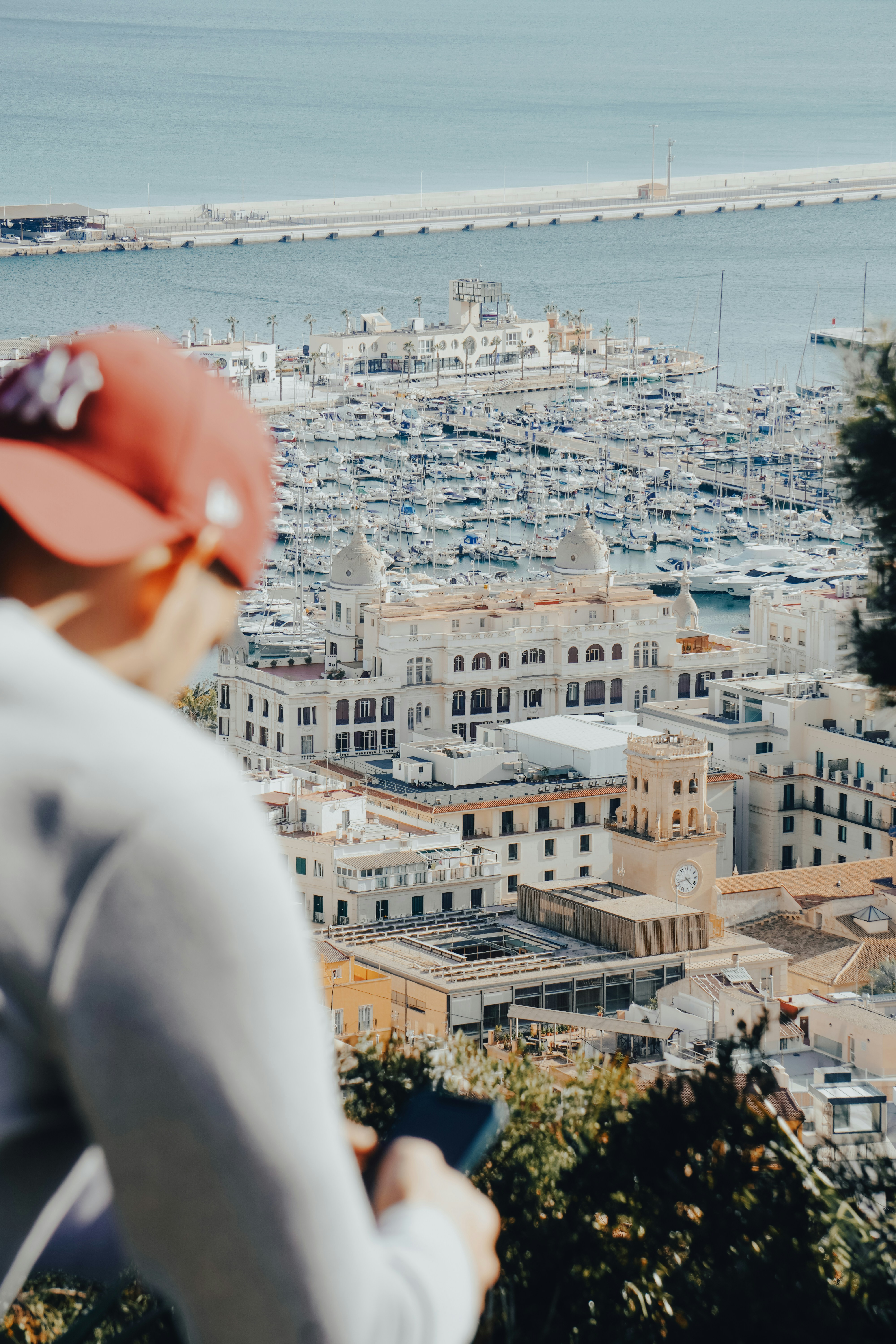Person overlooks a coastal city with boats and buildings.