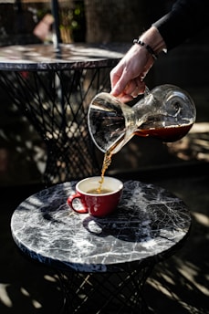 Coffee is being poured into a red cup.