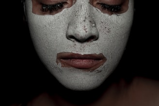 Person wearing a white face mask with closed eyes.