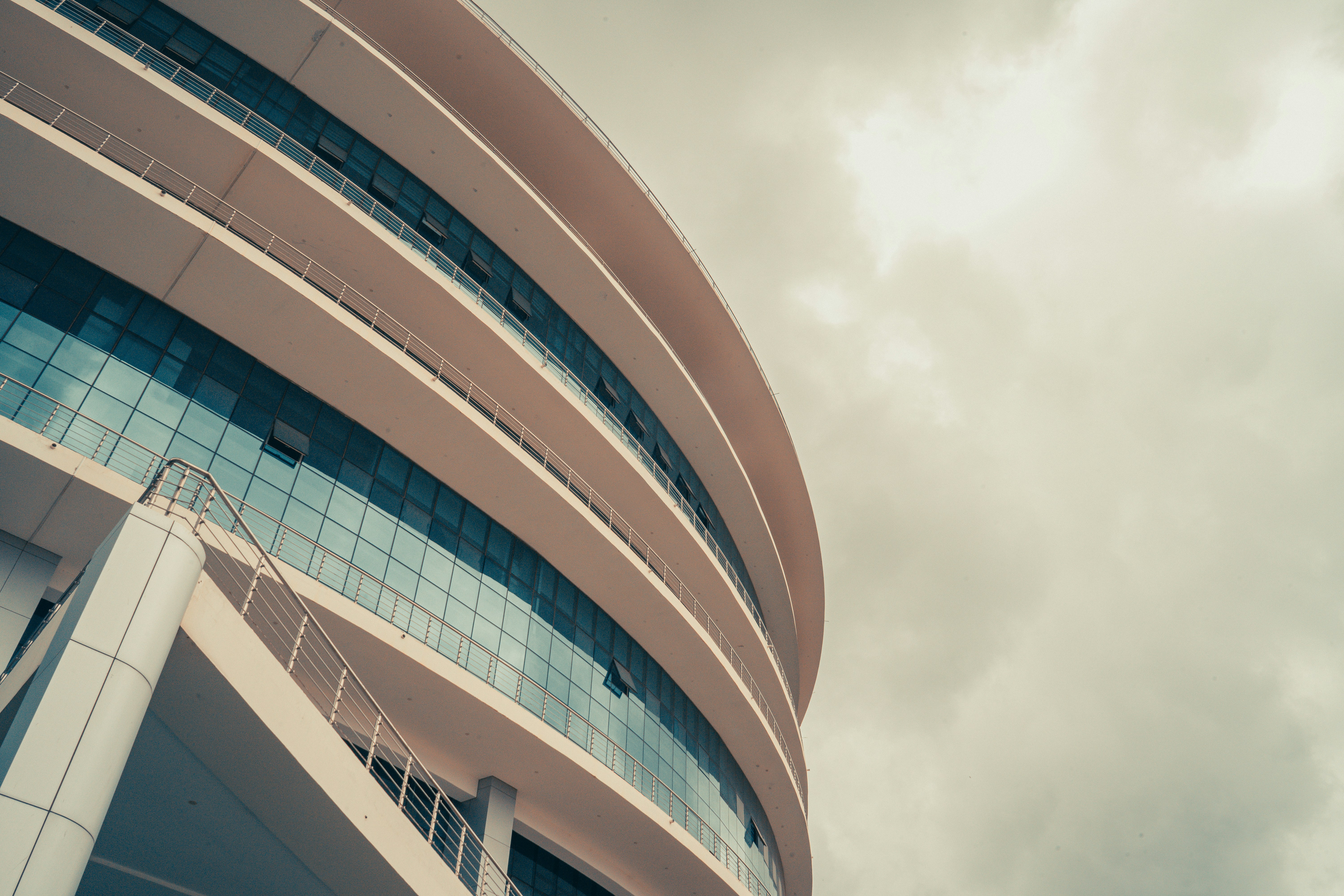 A modern building rises against a cloudy sky.