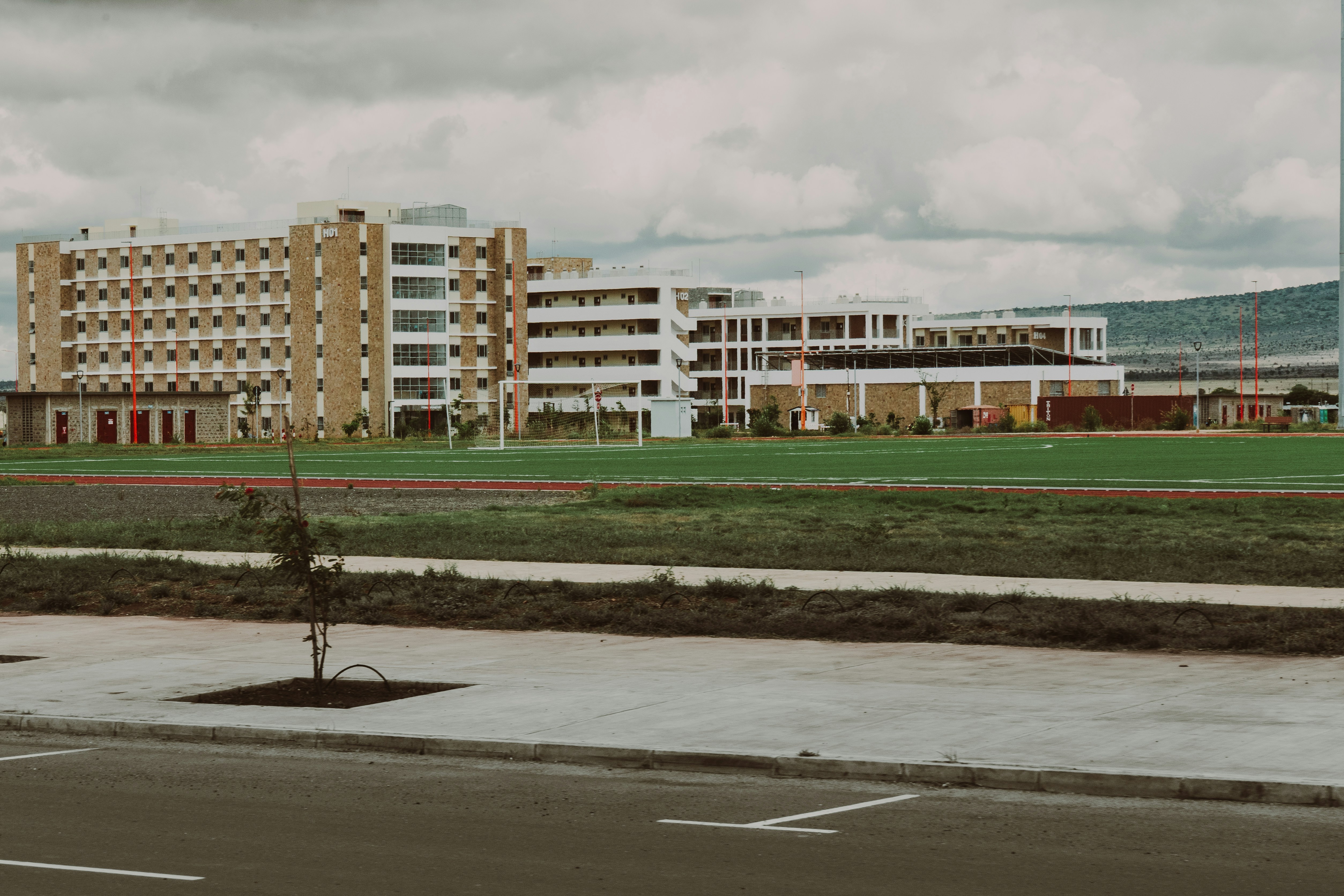 A modern building is seen on a green field.