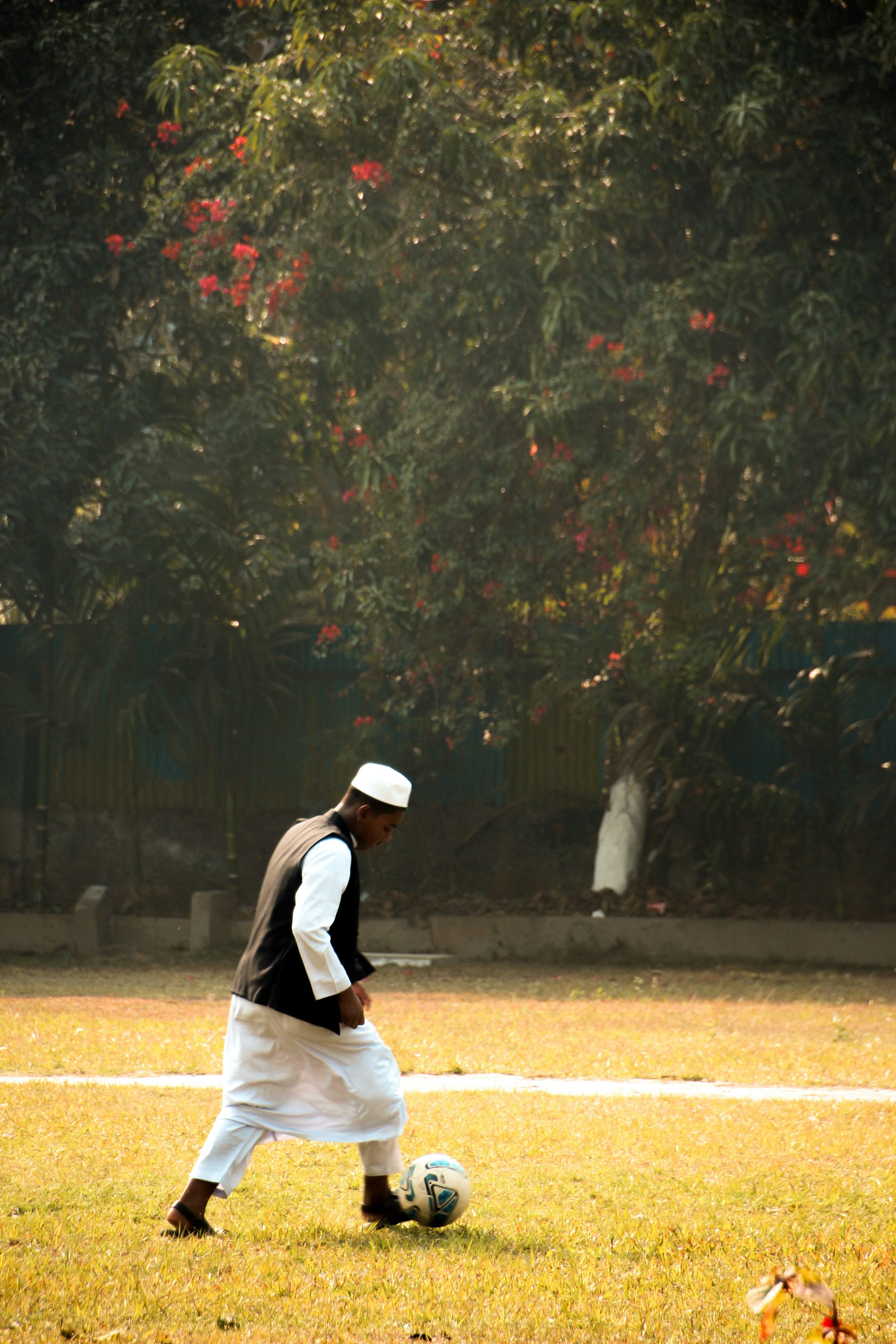 Pria bermain sepak bola di lapangan rumput.