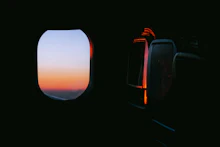 A traveler working on a laptop beside an airplane window