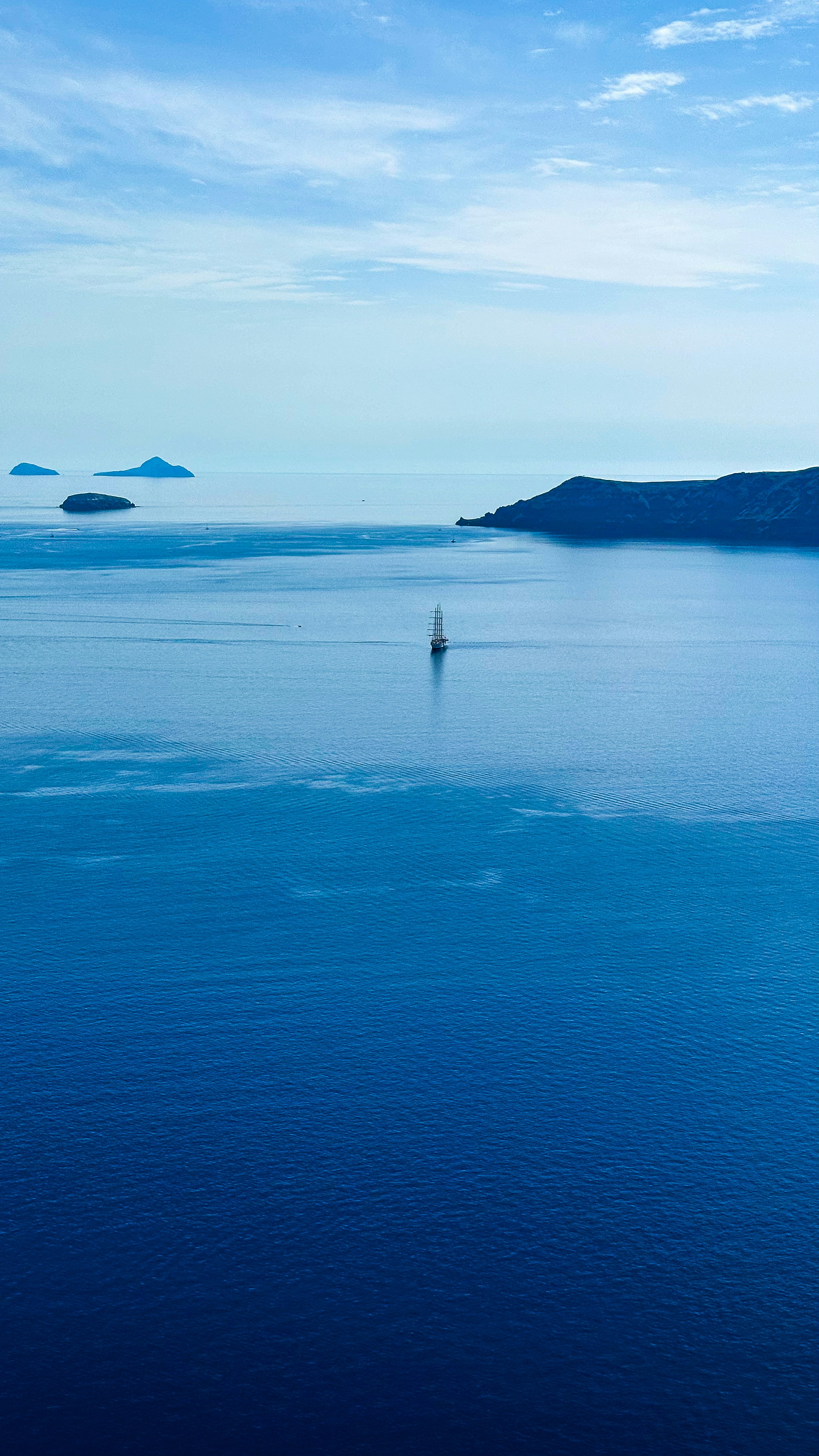 A sailboat cruises through calm waters.