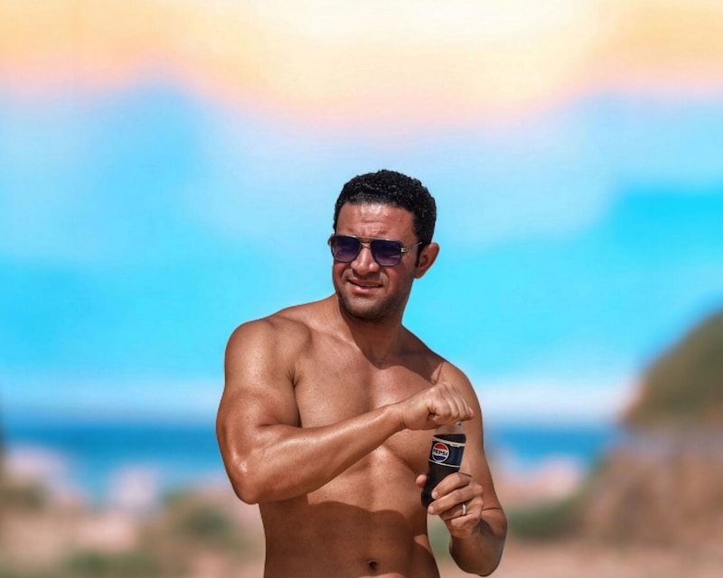 Handsome man on the beach opening a can.