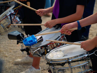 Drummers are playing drums with drumsticks.
