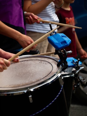 People are playing drums with drumsticks.