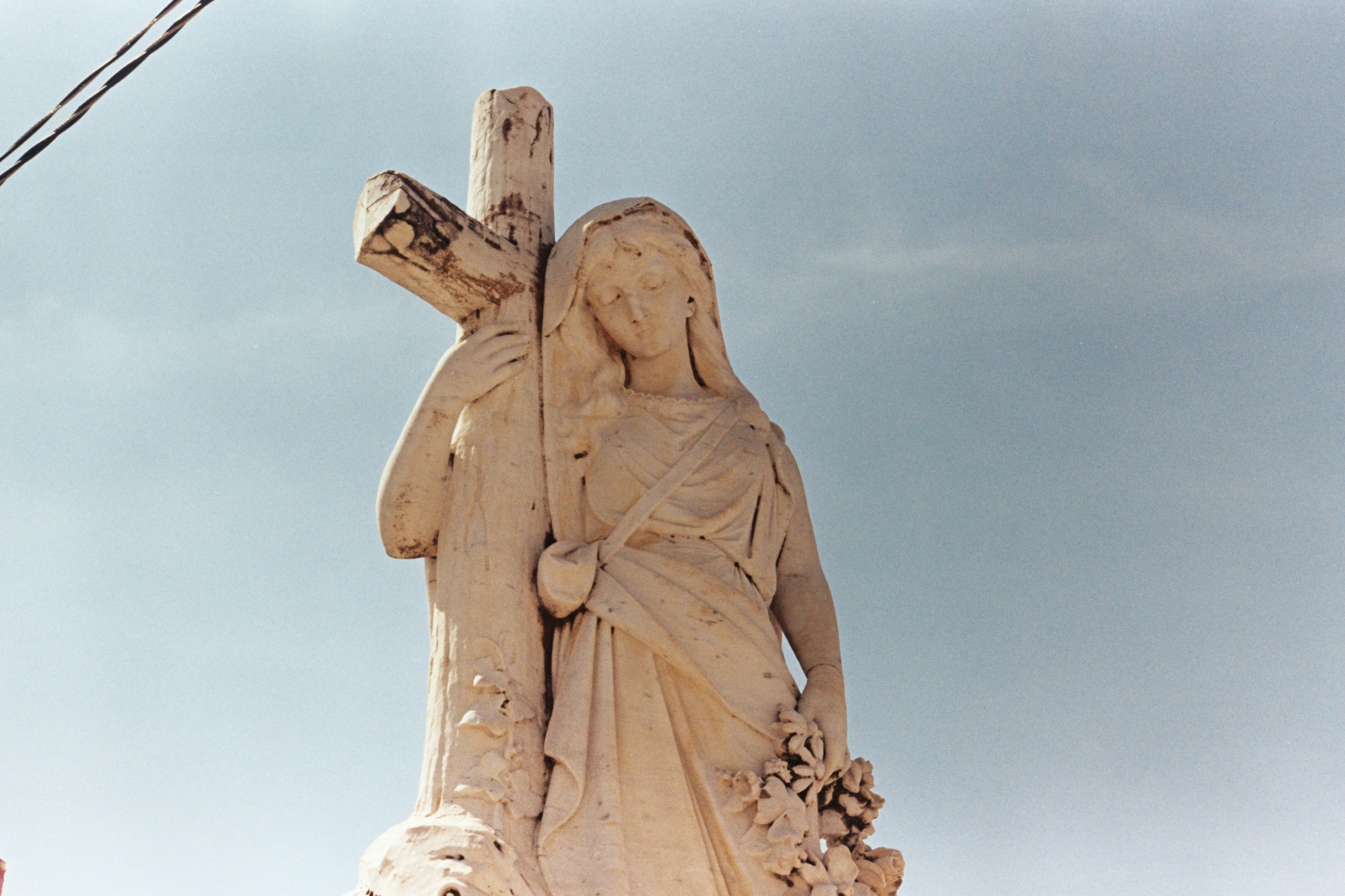 A marble statue of a woman and cross.