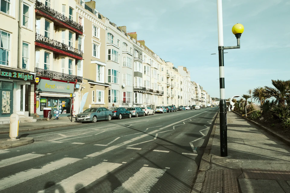 Tall white buildings with balconies and reflective windows line both sides of street