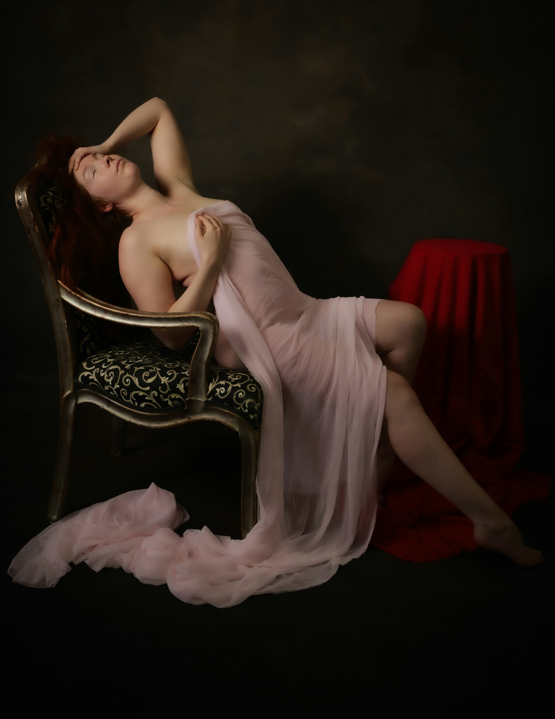 A woman poses elegantly in a sheer wrap.