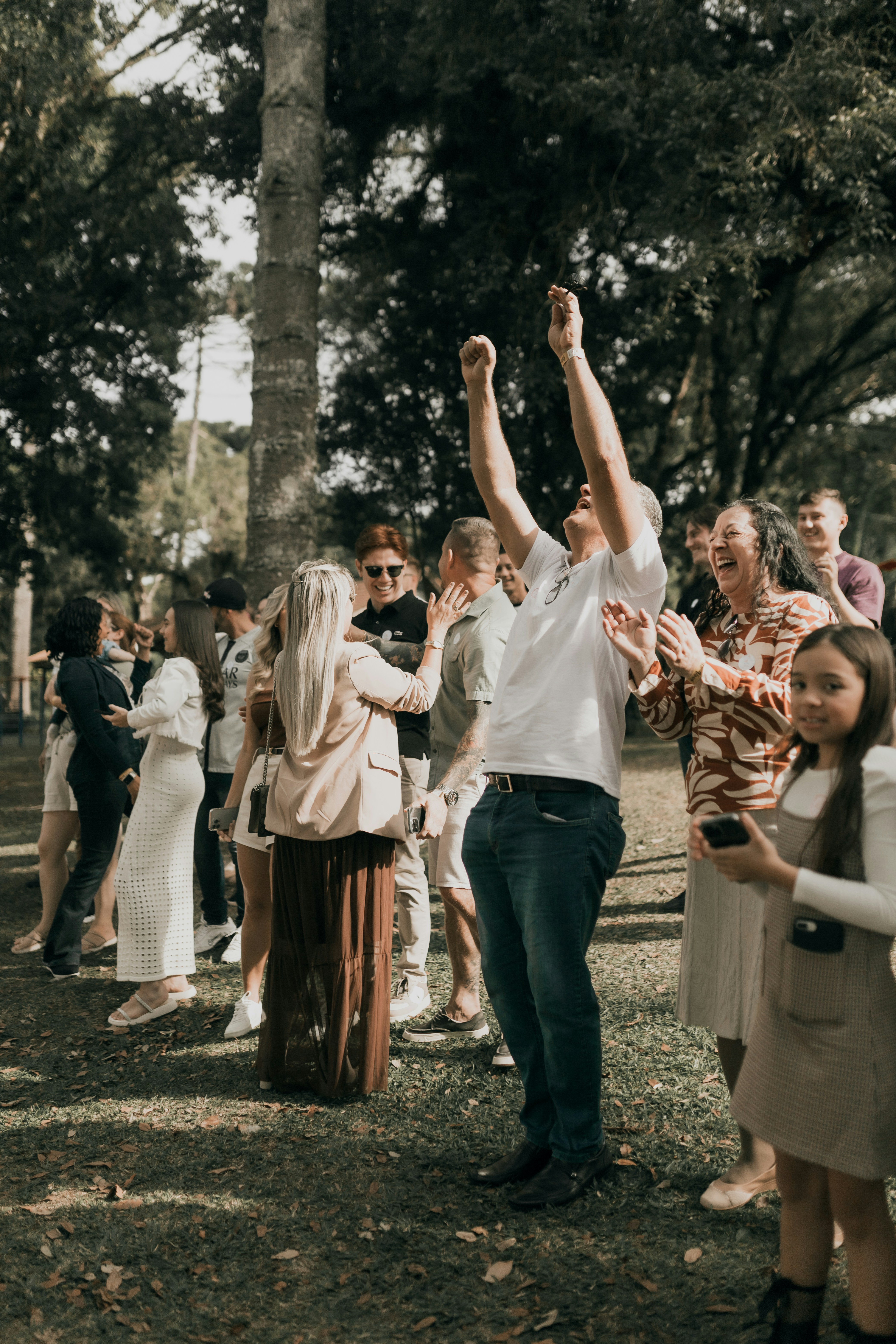 People celebrate and cheer together on a grassy lawn.
