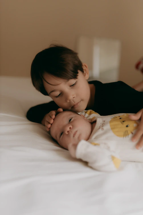 Older brother tenderly cuddles baby brother.