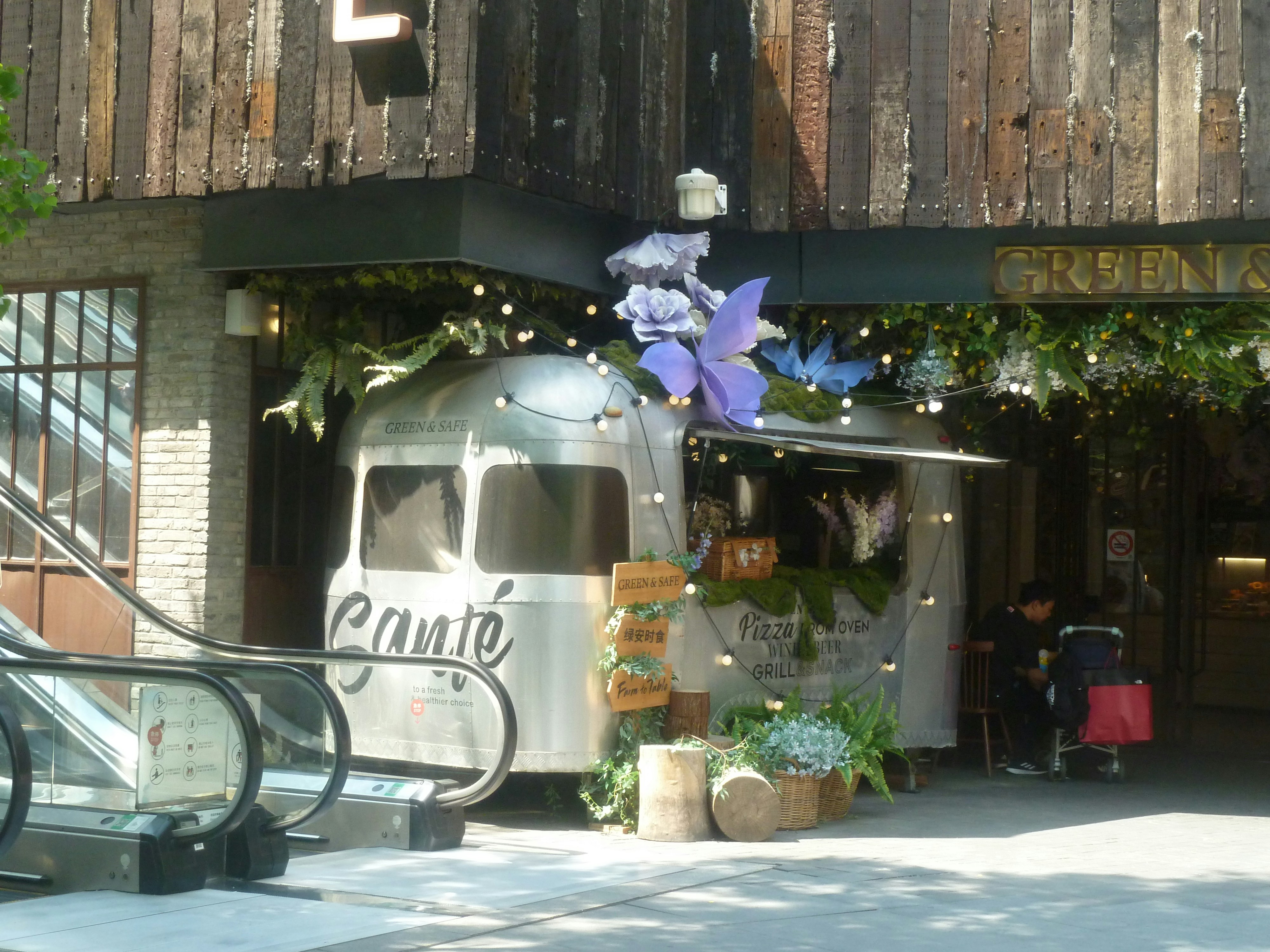 An attractive food truck sits below a wooden building.