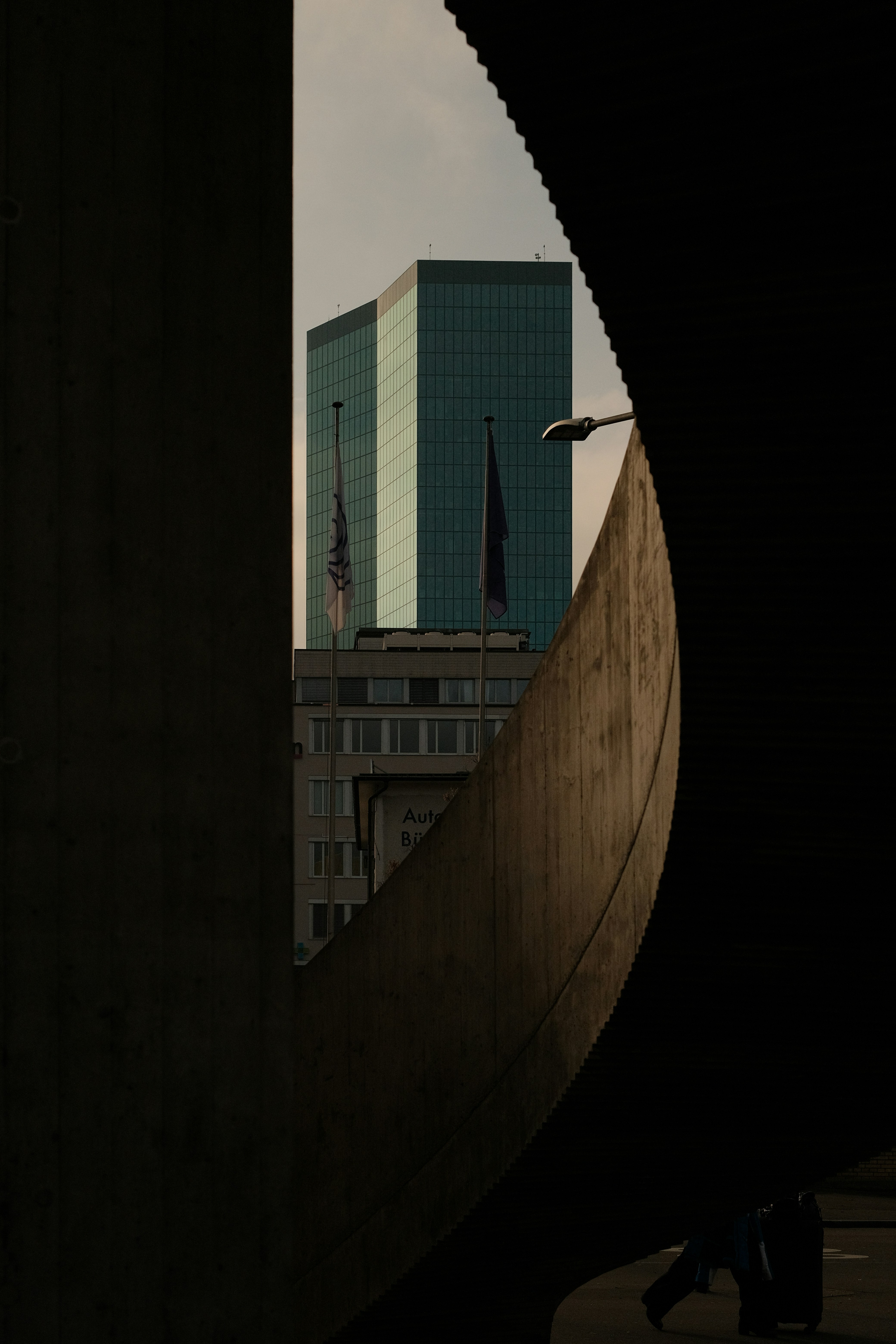 Building peeking through a curved, dark structure.
