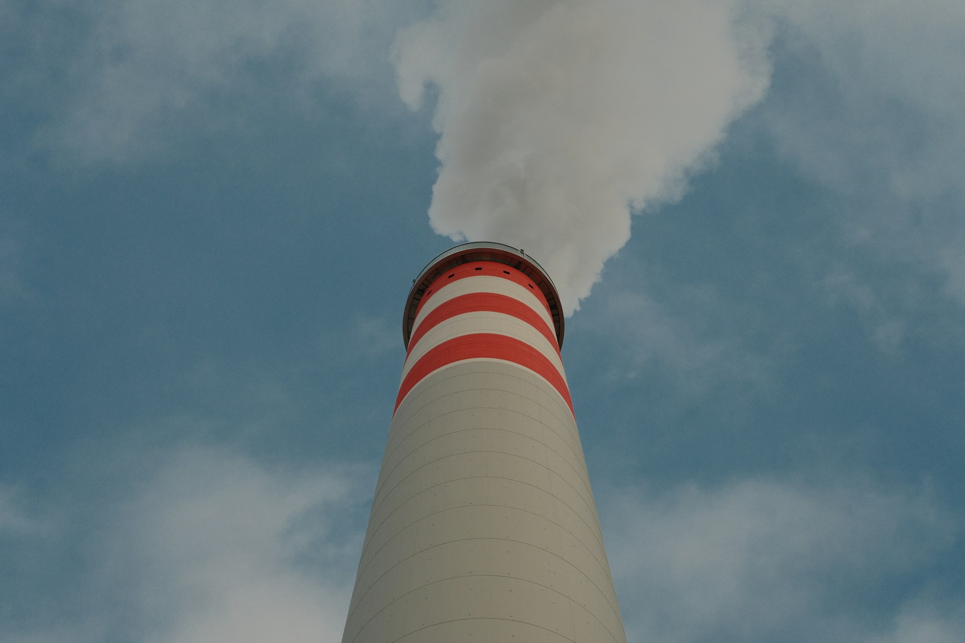 Smoke billows from a tall industrial chimney.