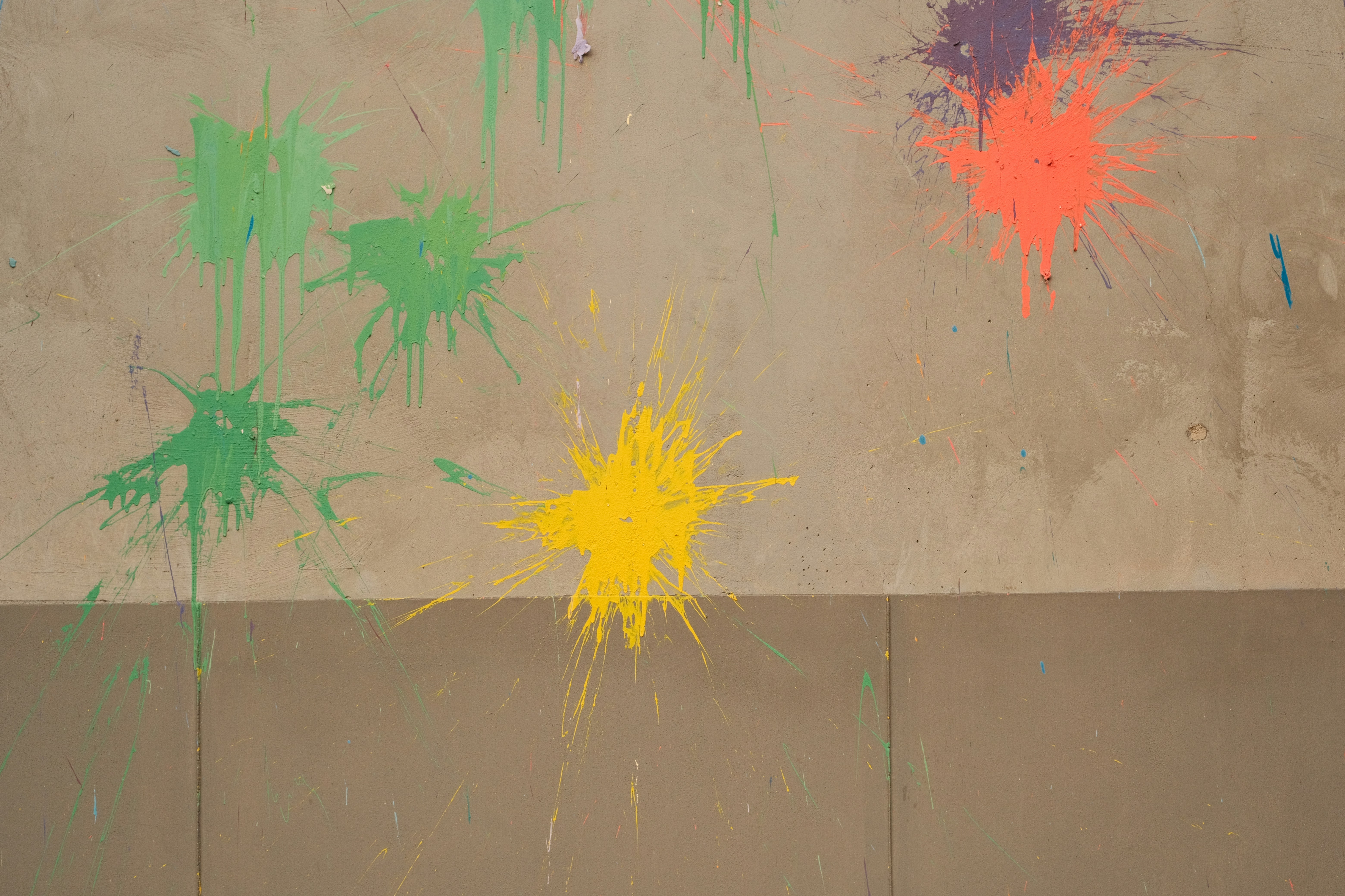 Paint splatters adorn a wall in vibrant colors.