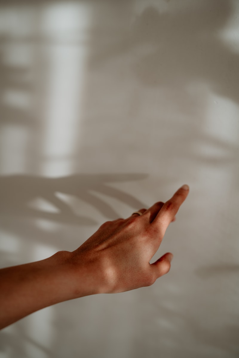 A hand reaching toward soft shadows on a wall