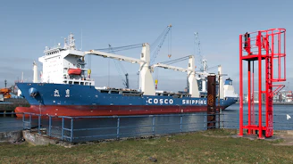 A large cosco shipping ship is docked at a port.