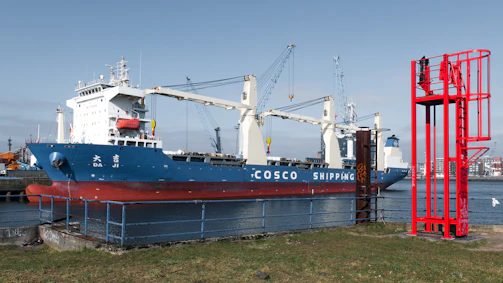 A large cosco shipping ship is docked at a port.