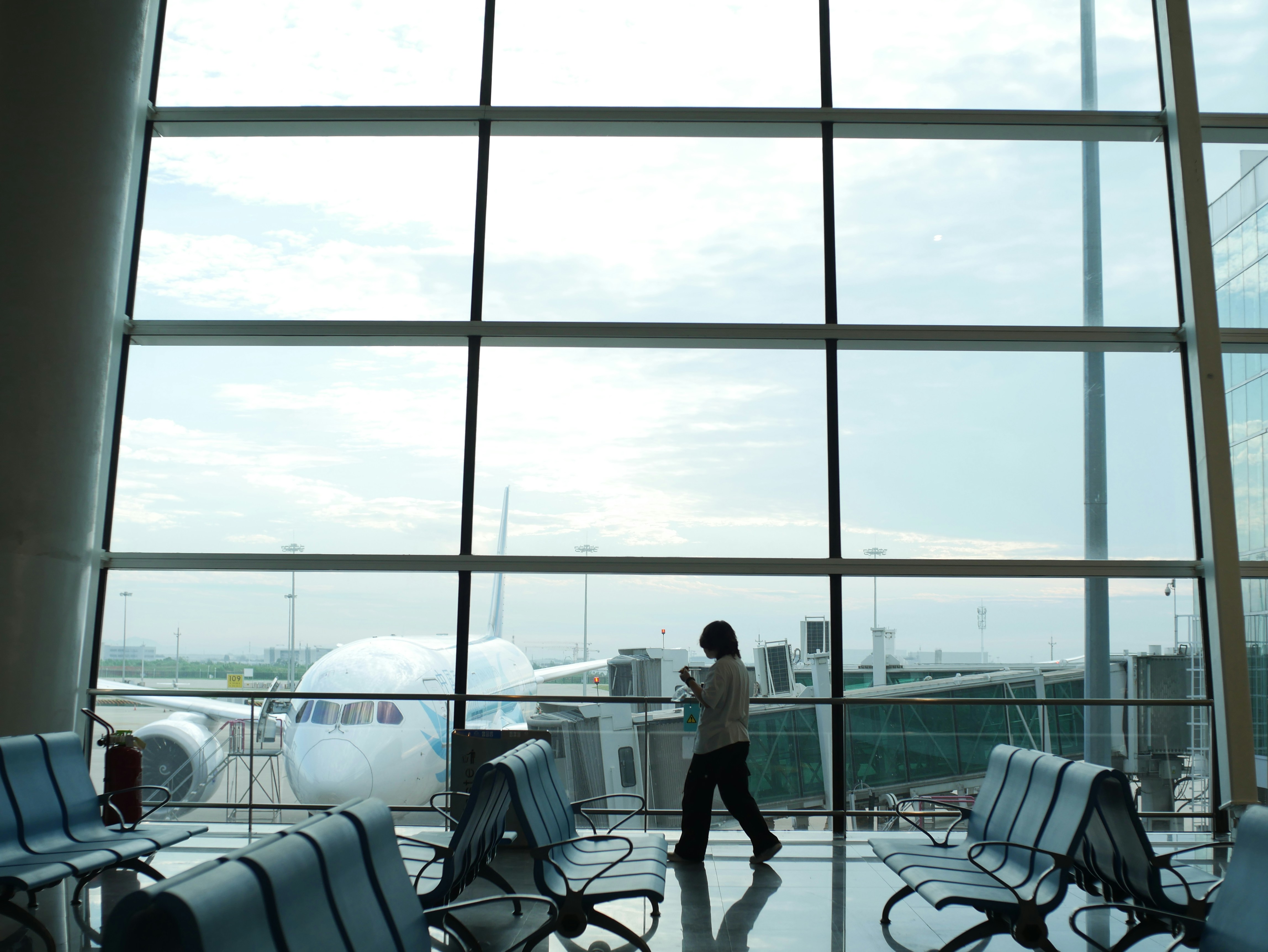 A person looks out an airport window at a plane., Waiting at the airport