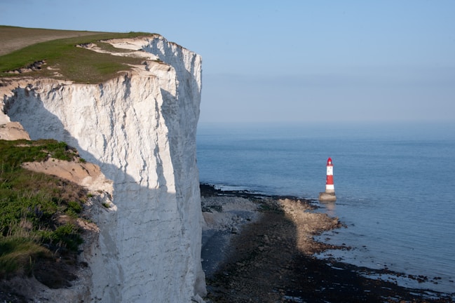 White cliffs and a lighthouse overlook the sea.