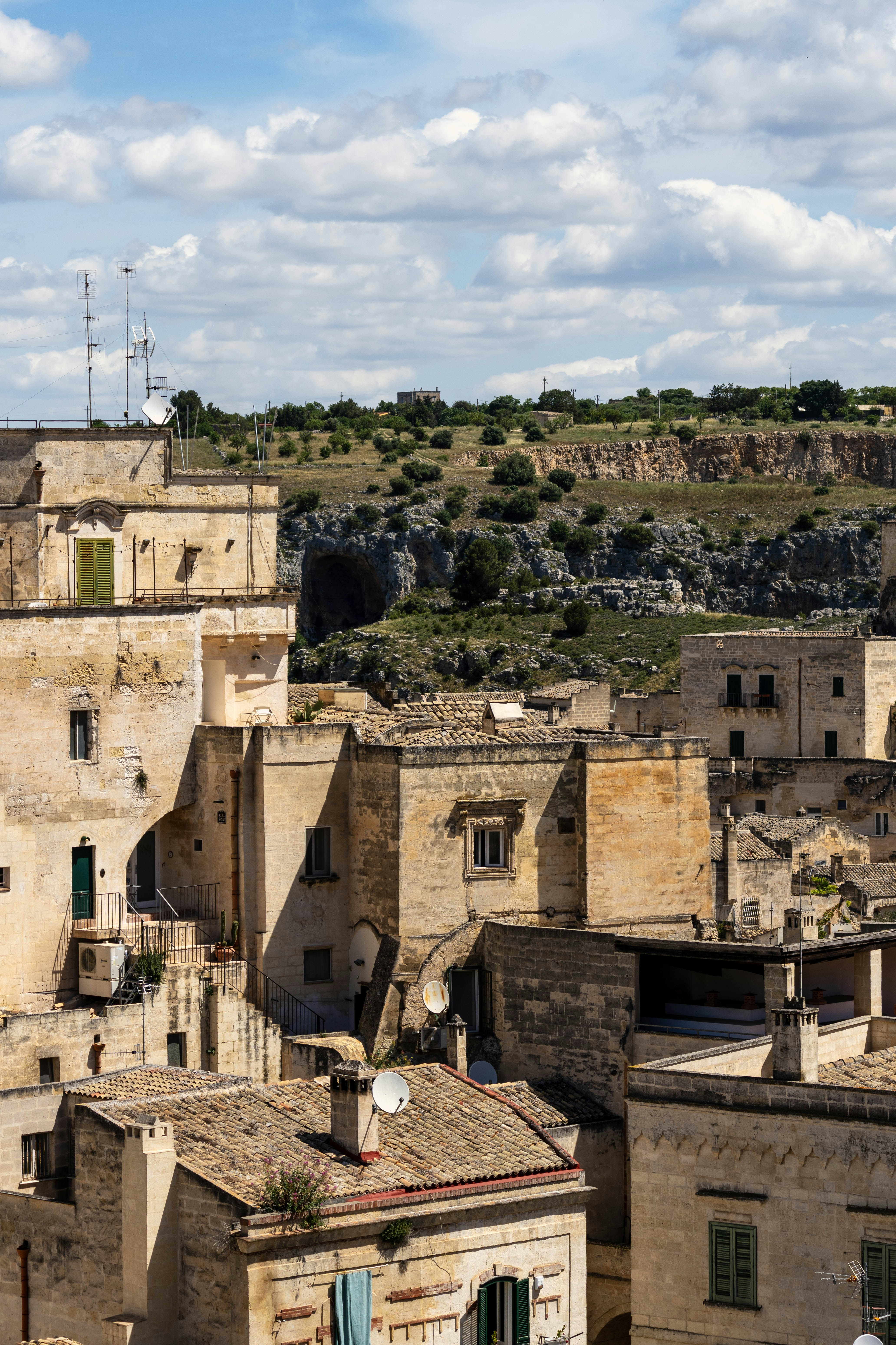 Old, beige buildings under a bright, cloudy sky.