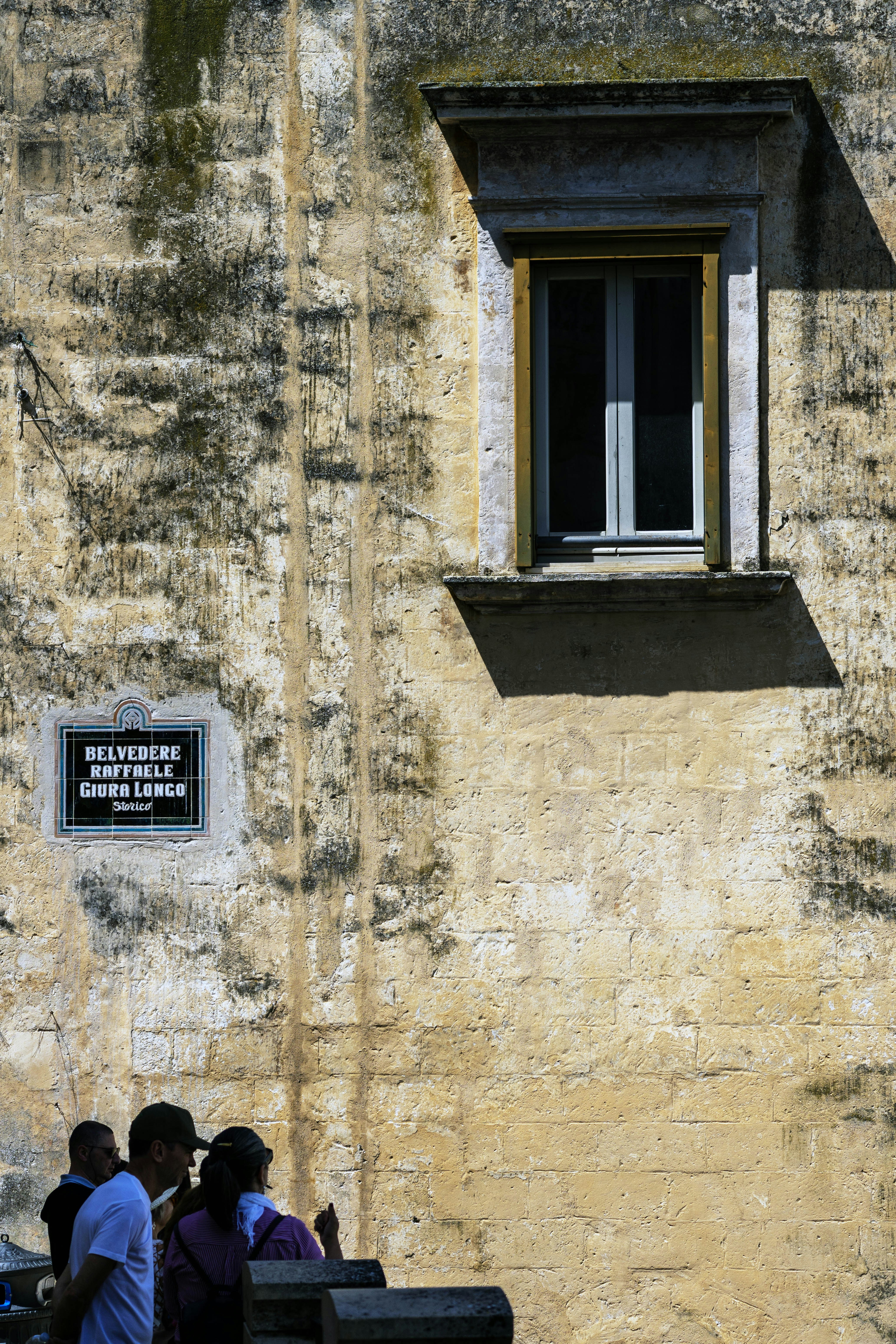 A window casts a shadow on a weathered wall.