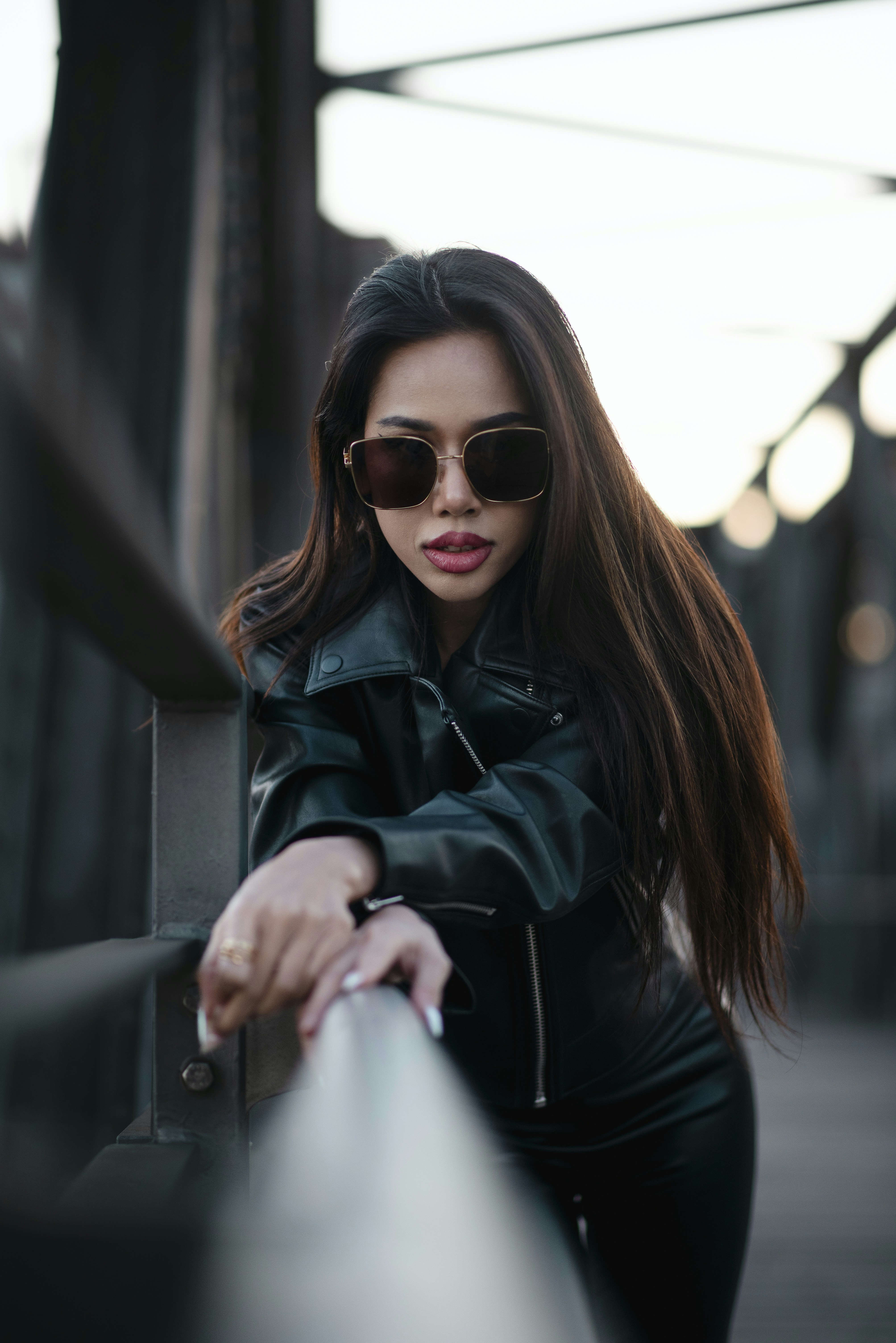 Woman posing confidently in sunglasses and a leather jacket.
