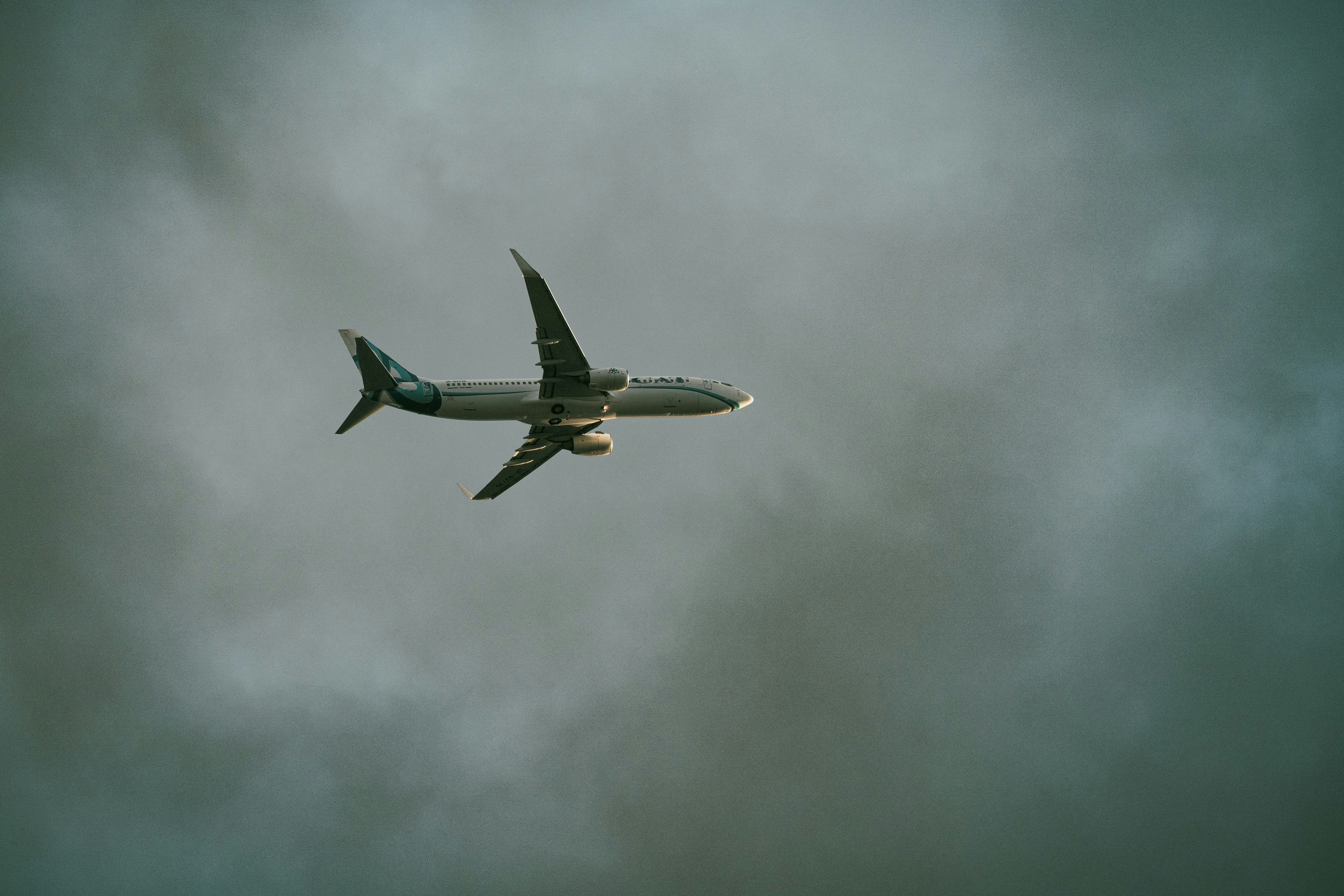 Airplane soaring through a cloudy, overcast sky.