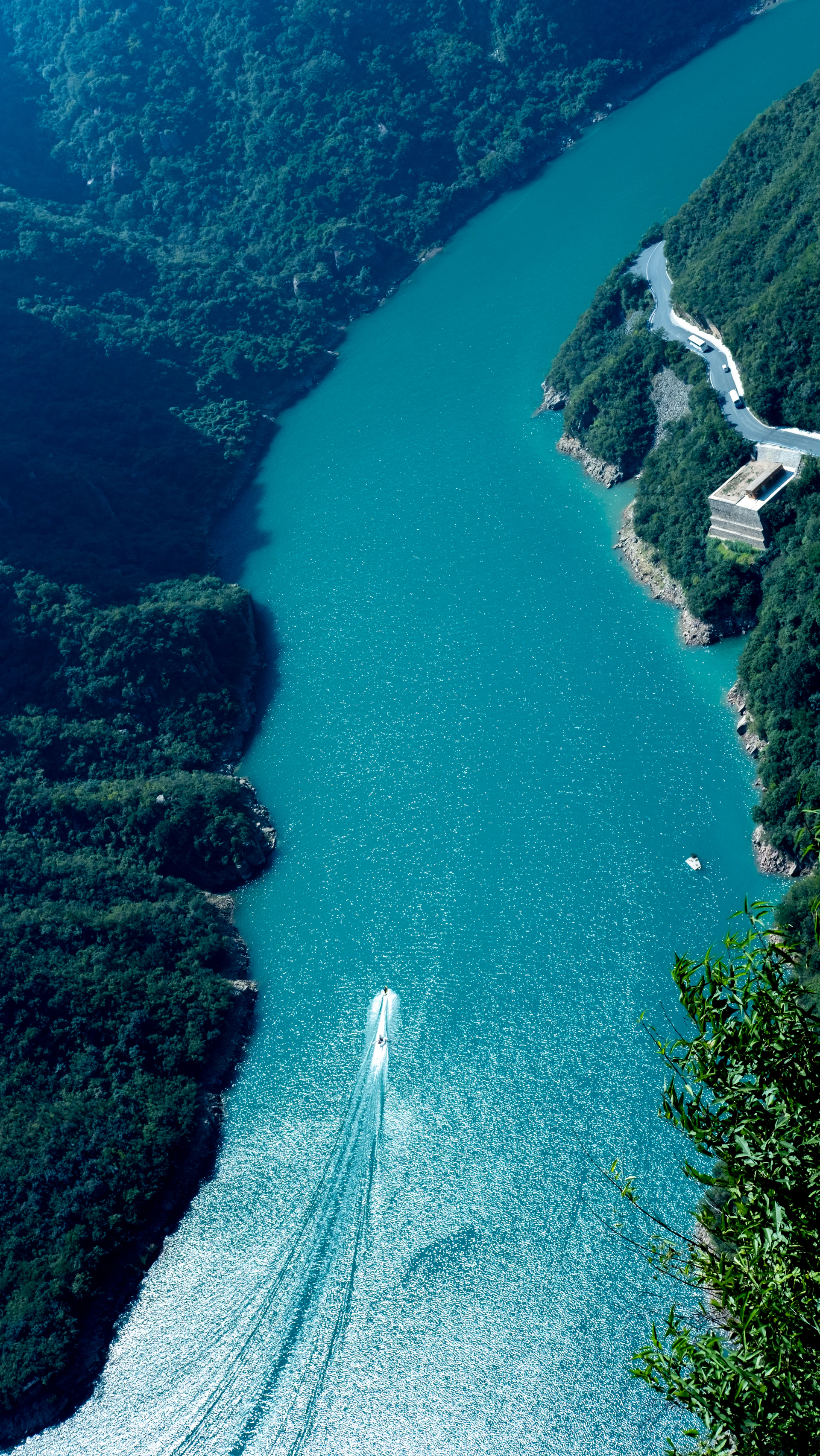 A boat trails on a turquoise river.