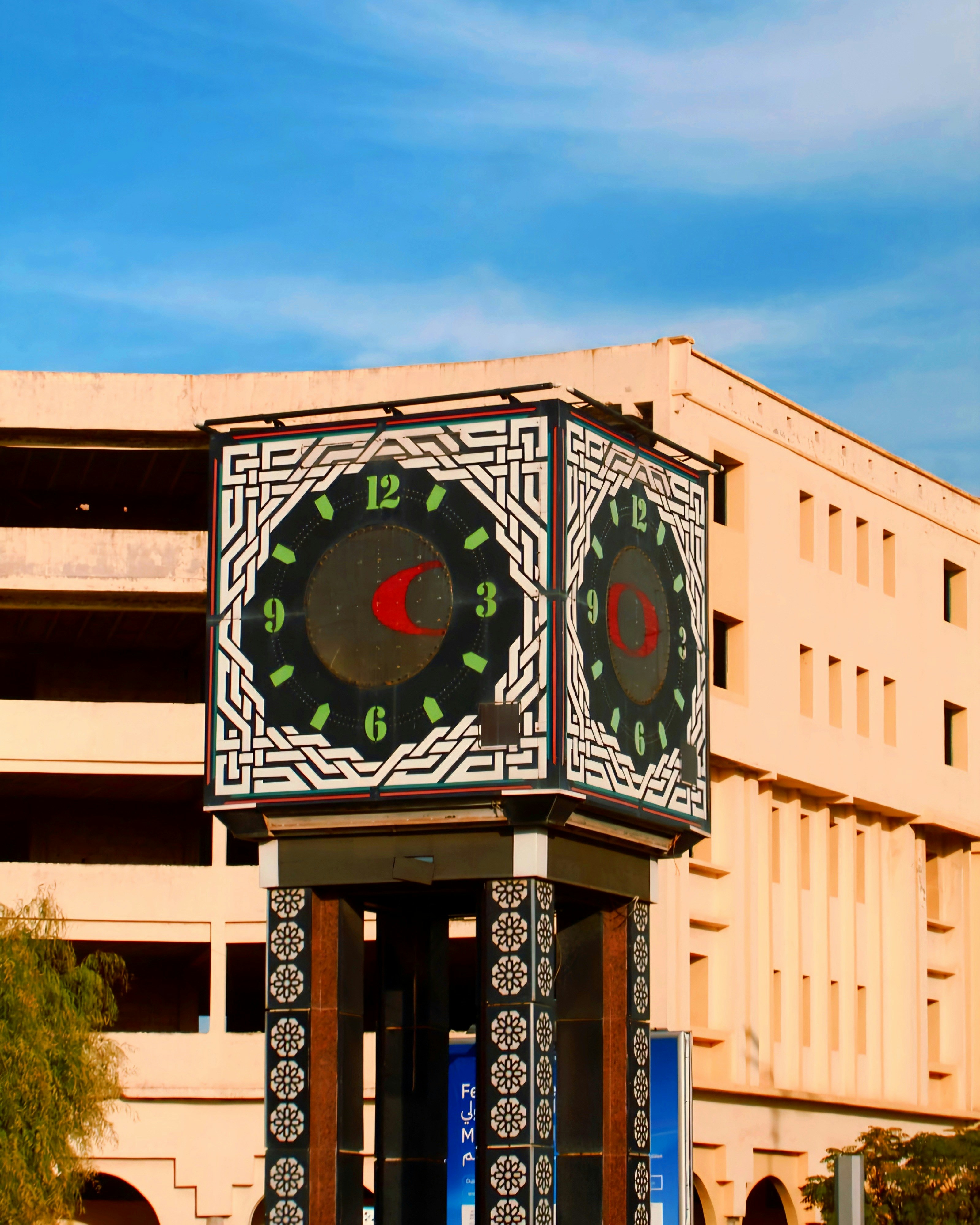 A decorative clock tower stands before a building.