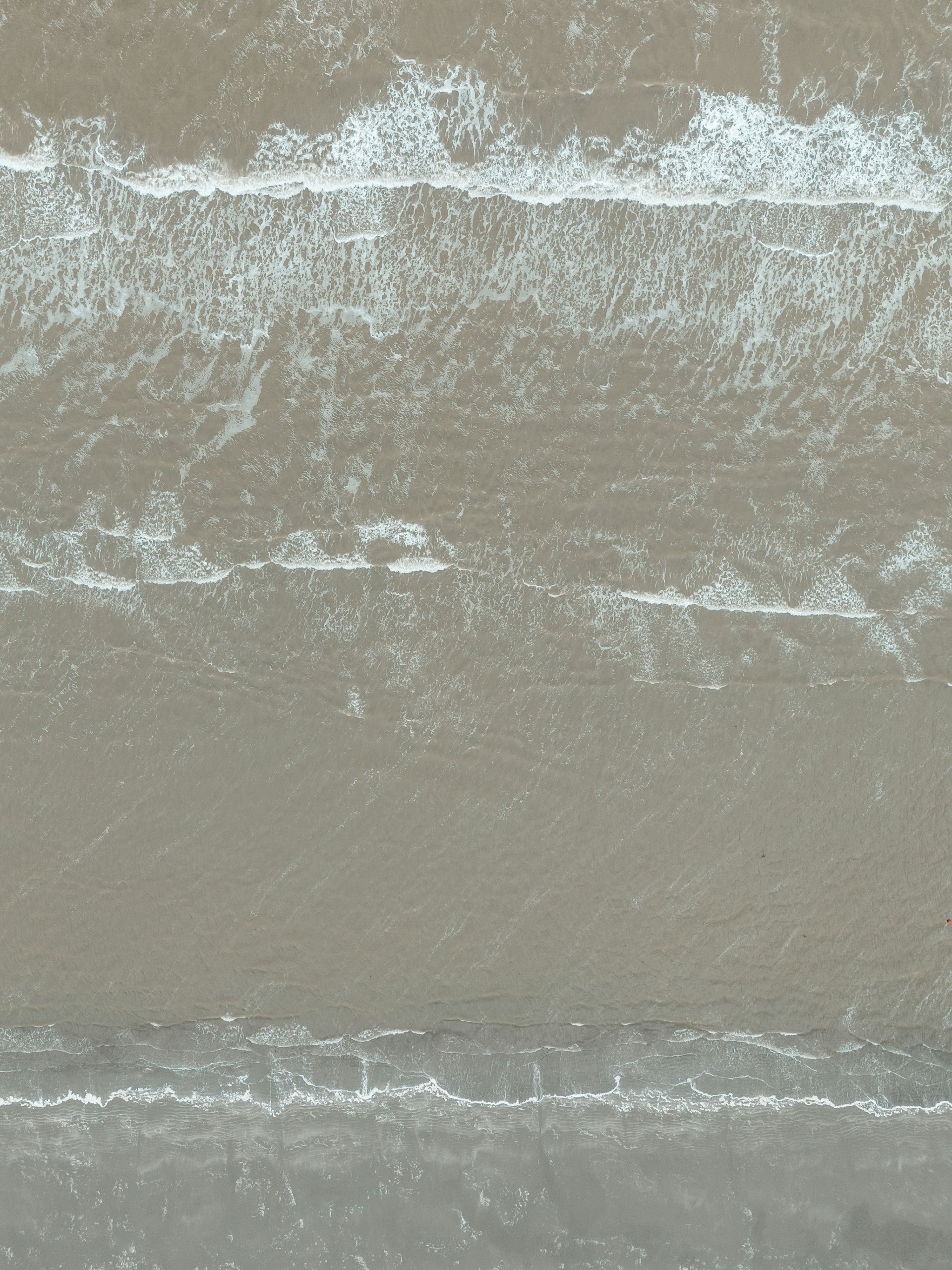 Waves crashing on the shore from an aerial view.