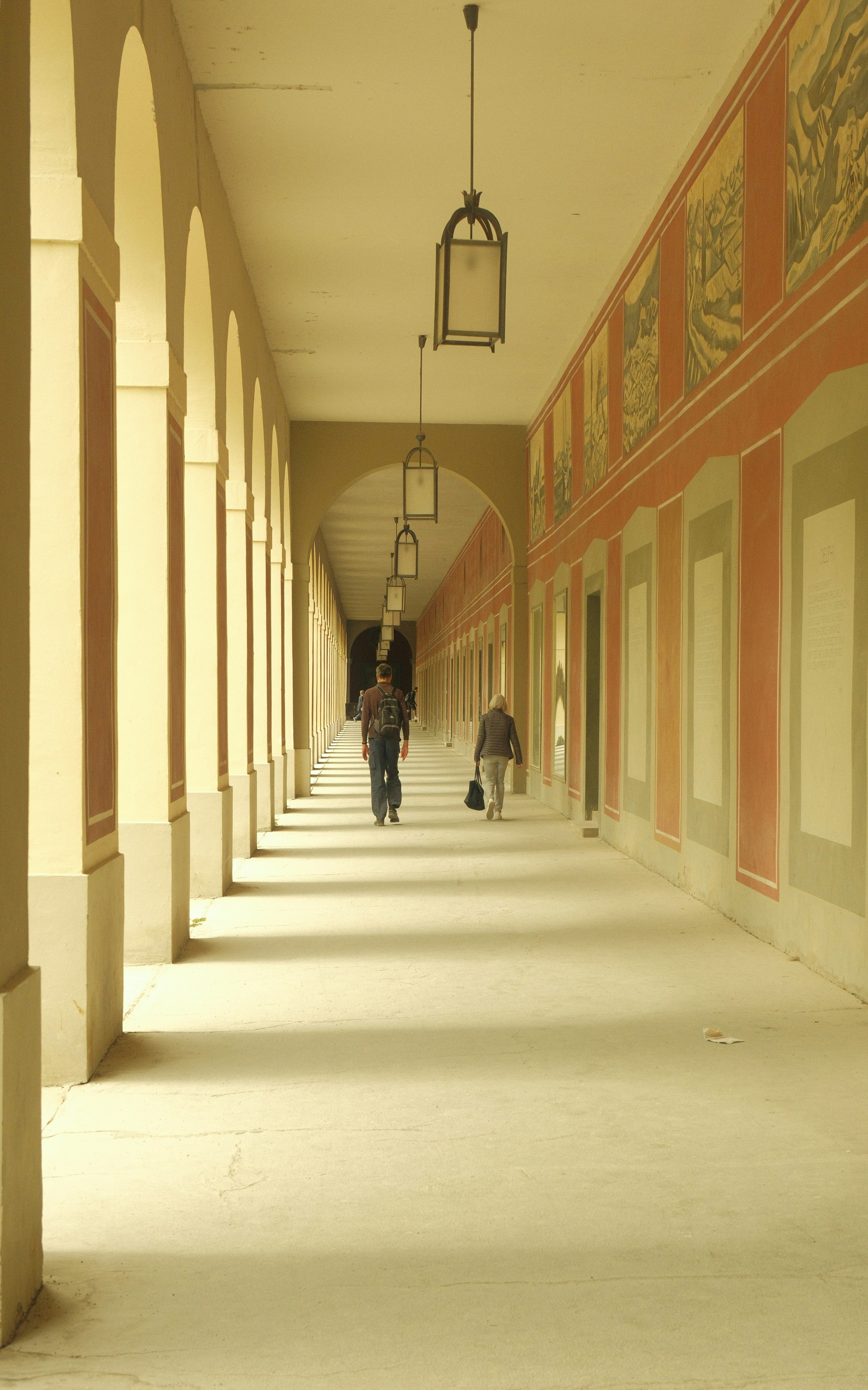 People walk through a long, arched hallway.