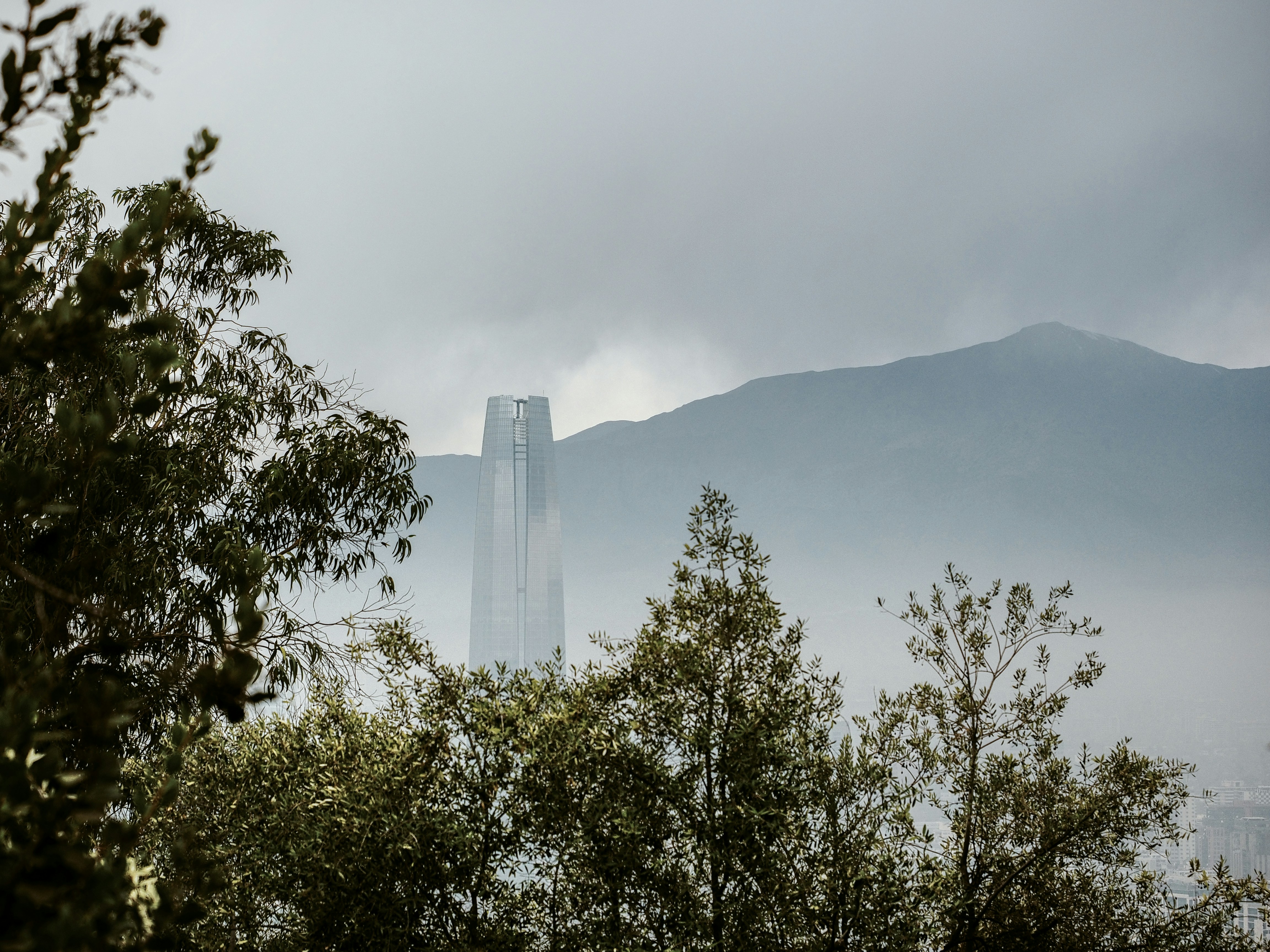 A tall building peeks through the hazy mountain.