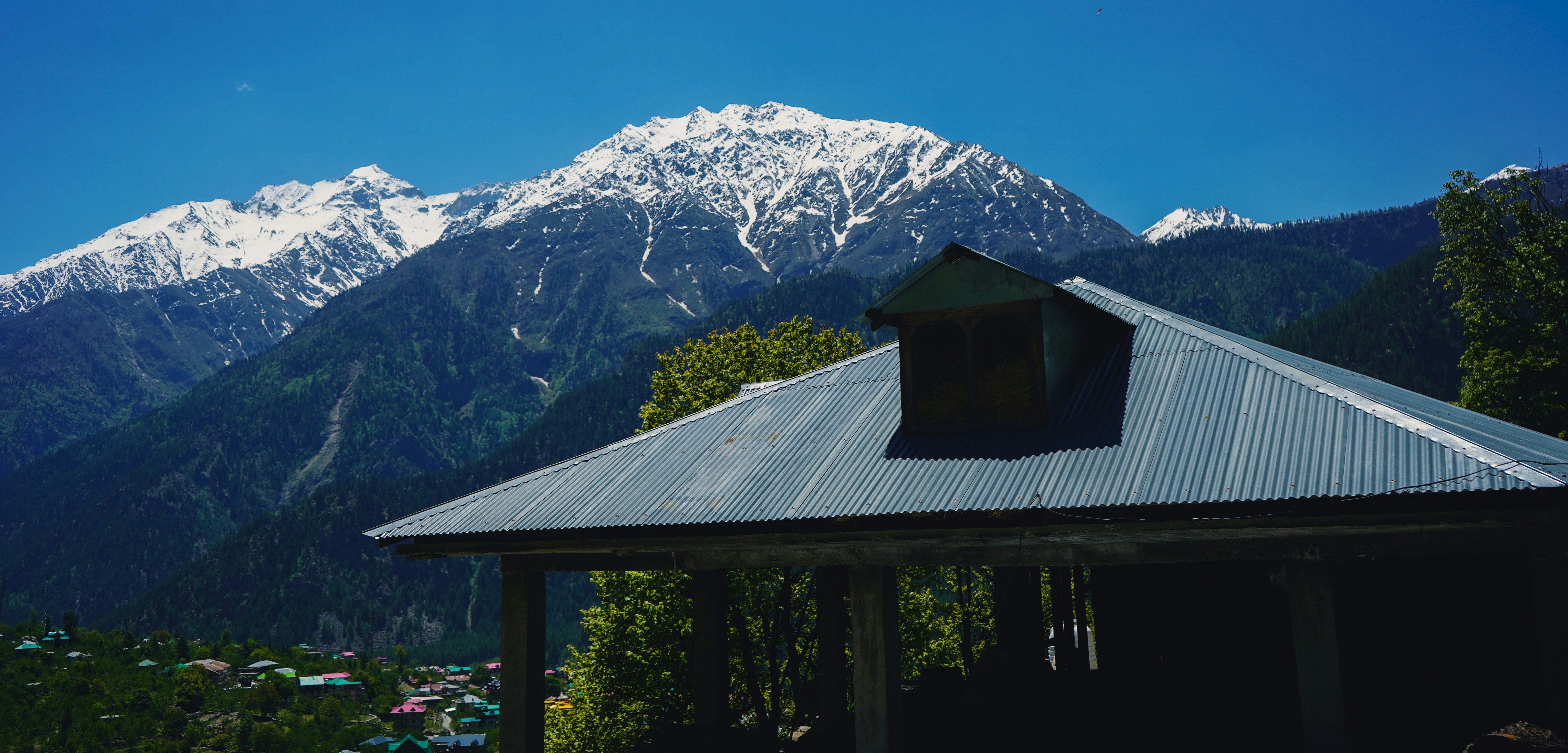 A cabin roof with snow-capped mountains in the background.