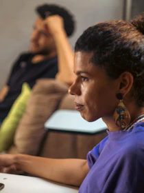 Woman looks ahead with a person in the background.