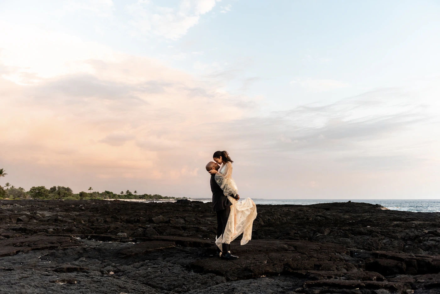 Couple during their elopement at Playa Mansa in Punta del Este with the calm river estuary water and the early morning light reflecting off the surface behind them
