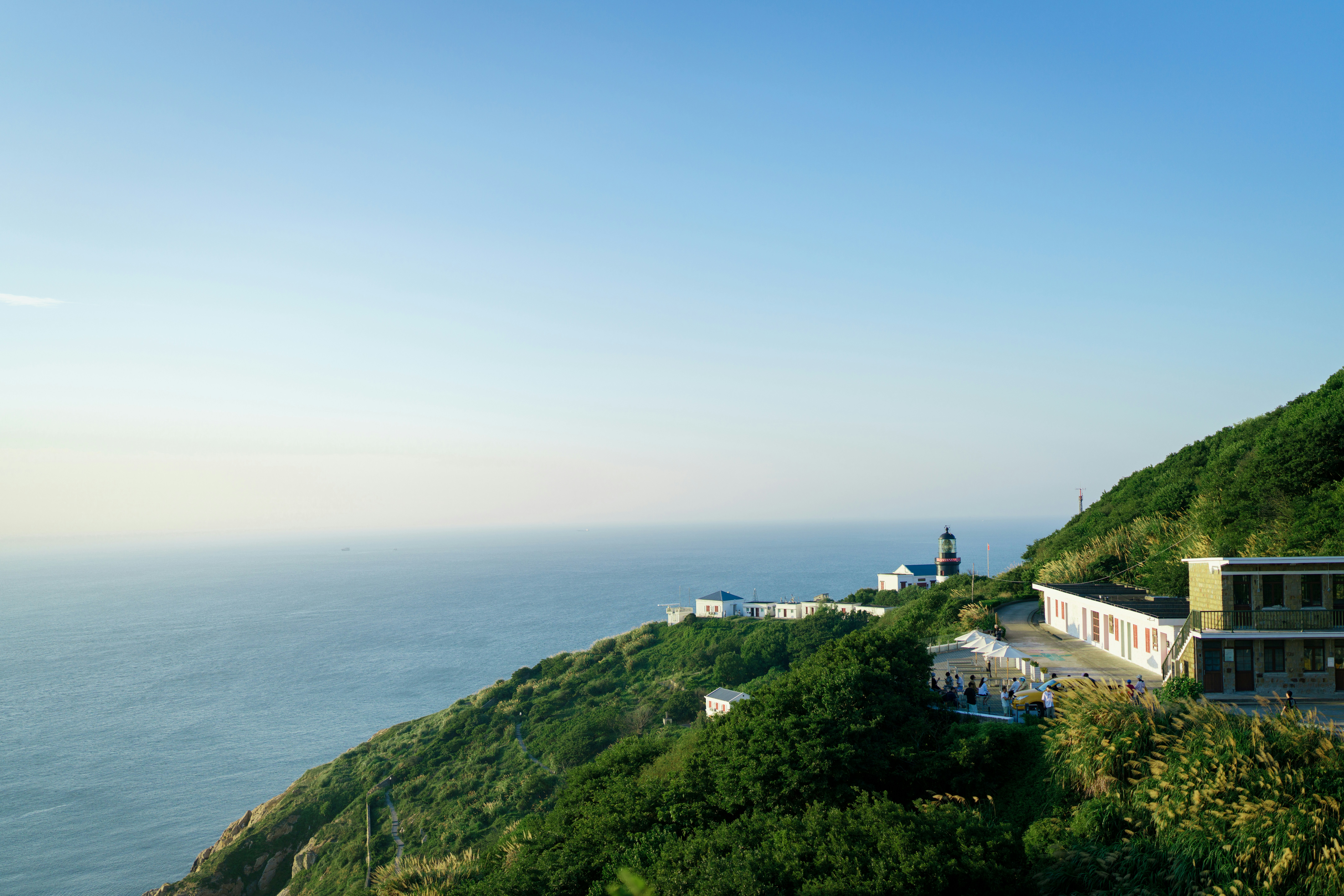 Lighthouse sits on a lush, green cliffside.