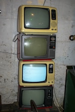 Four old television sets are stacked vertically.