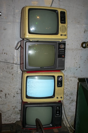 Four old television sets are stacked vertically.