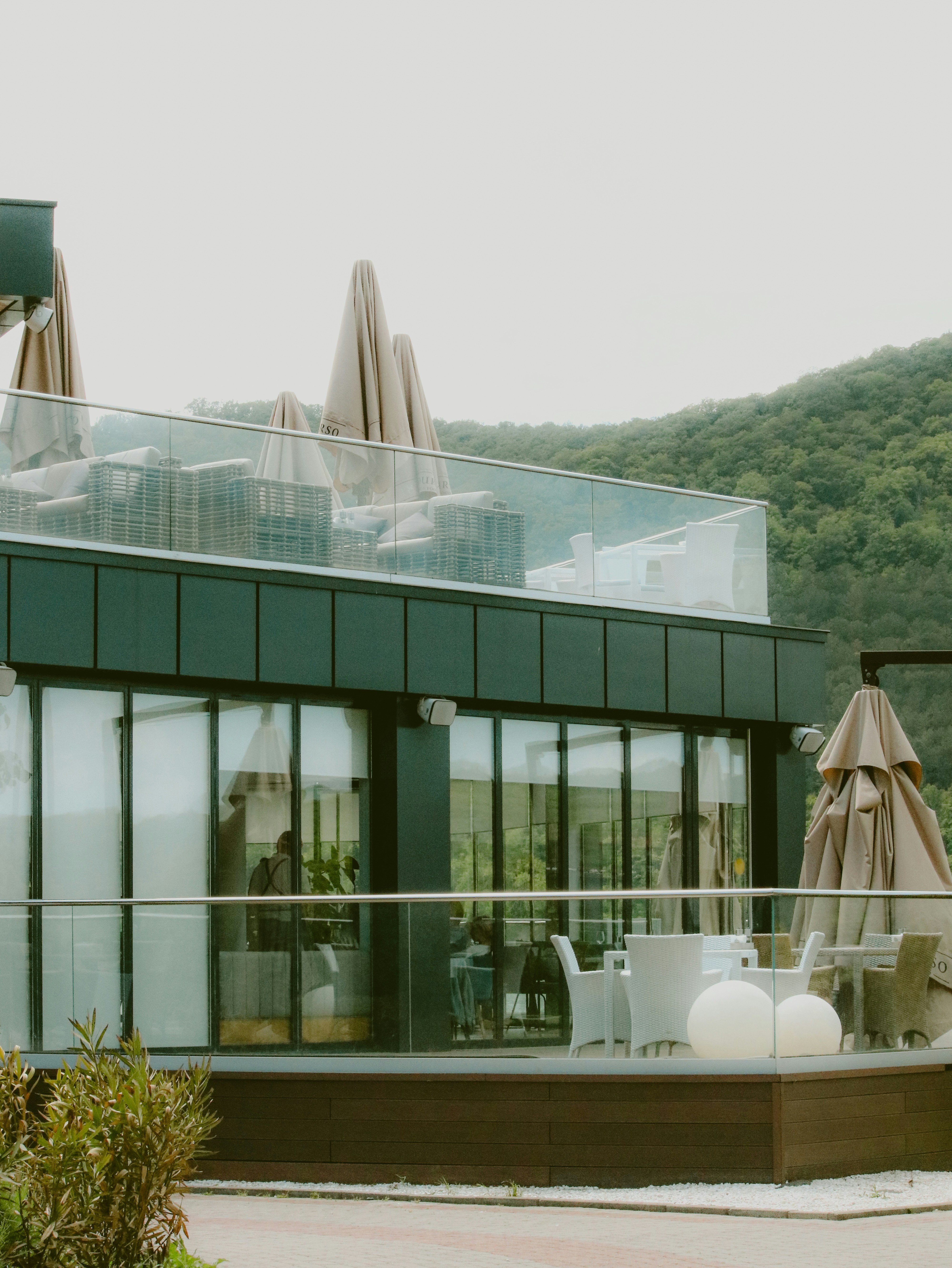 A restaurant with outdoor seating overlooks a mountain.