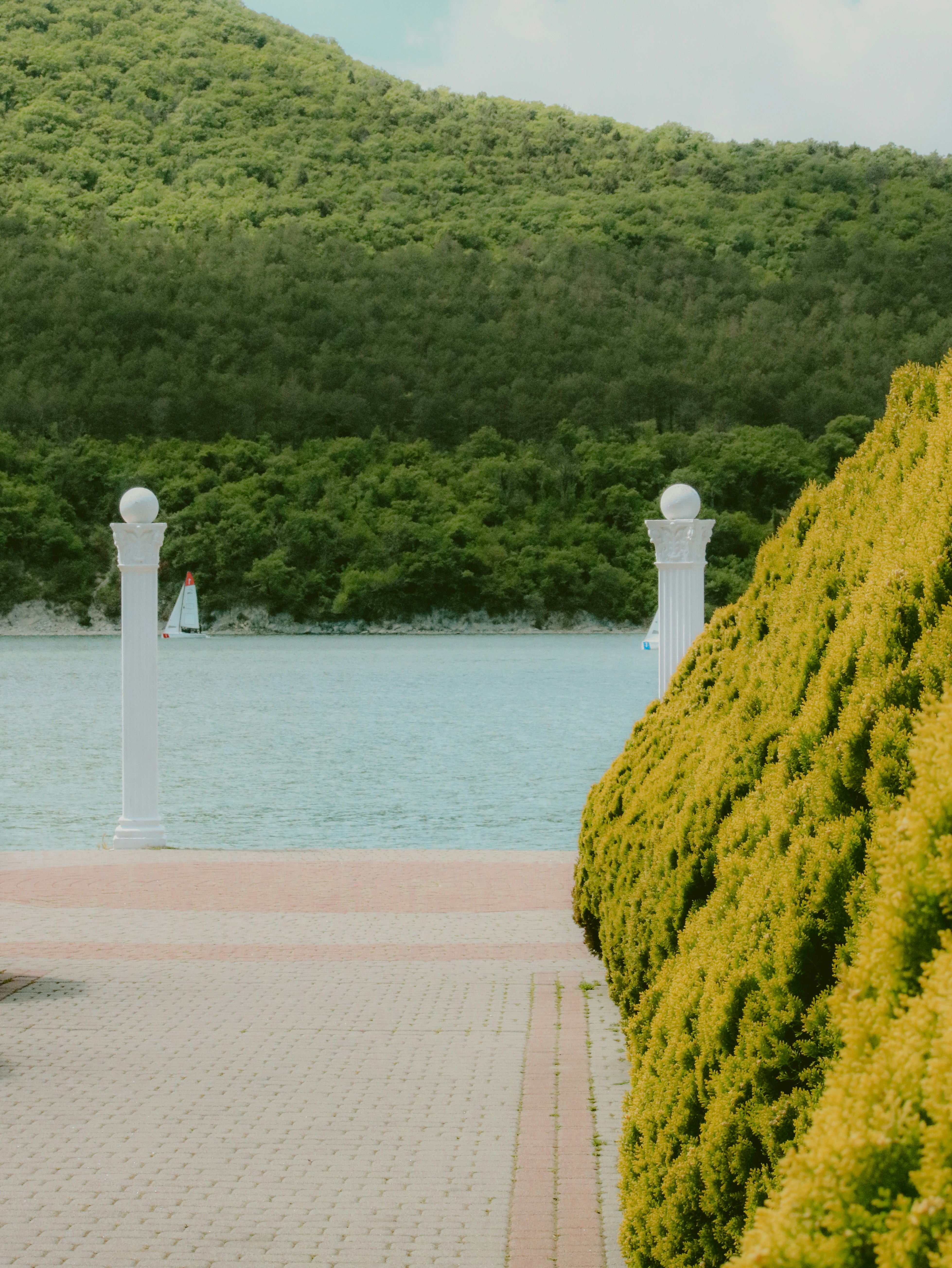 Green trees overlook a lake with white pillars.