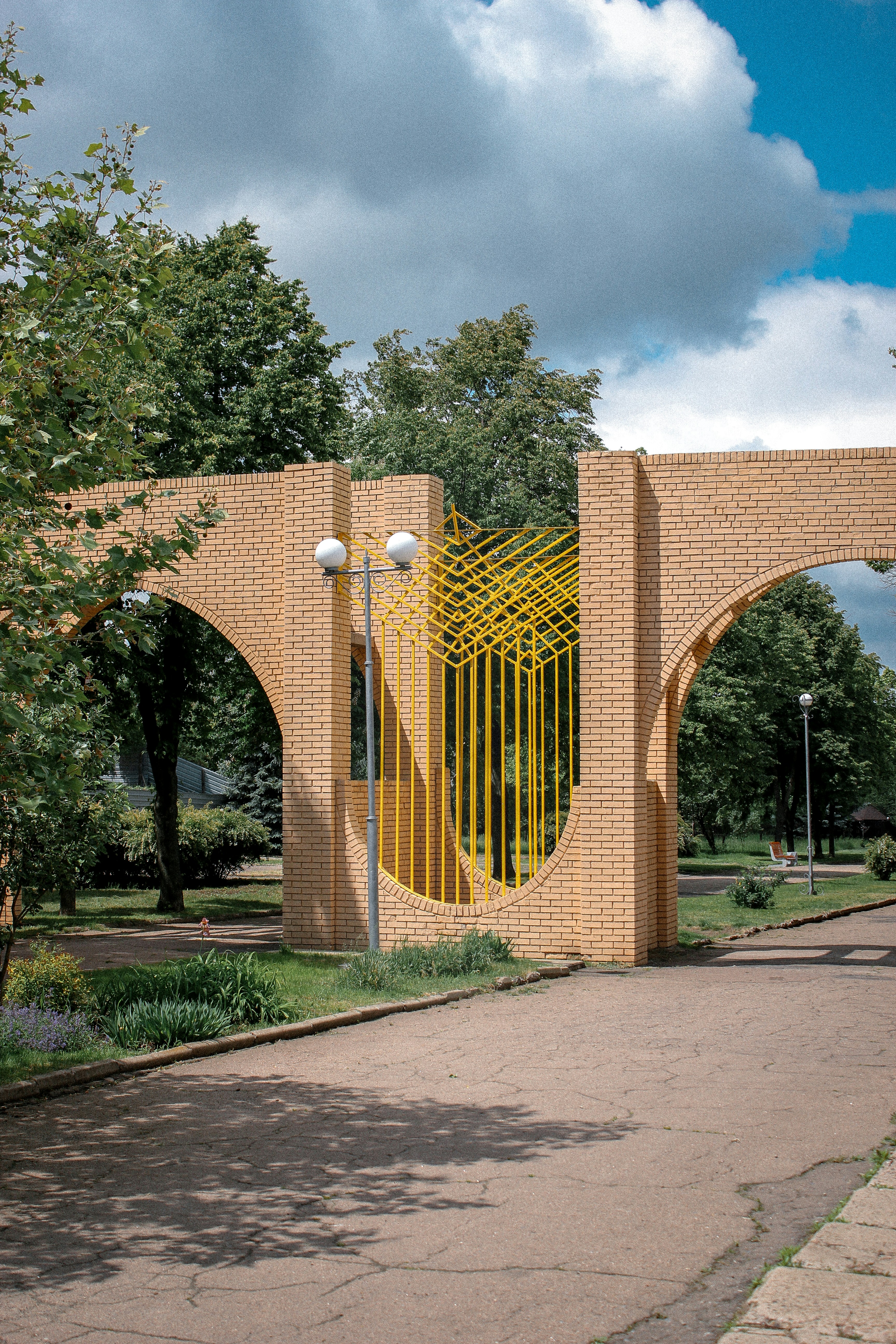 A brick archway stands in a sunny park.