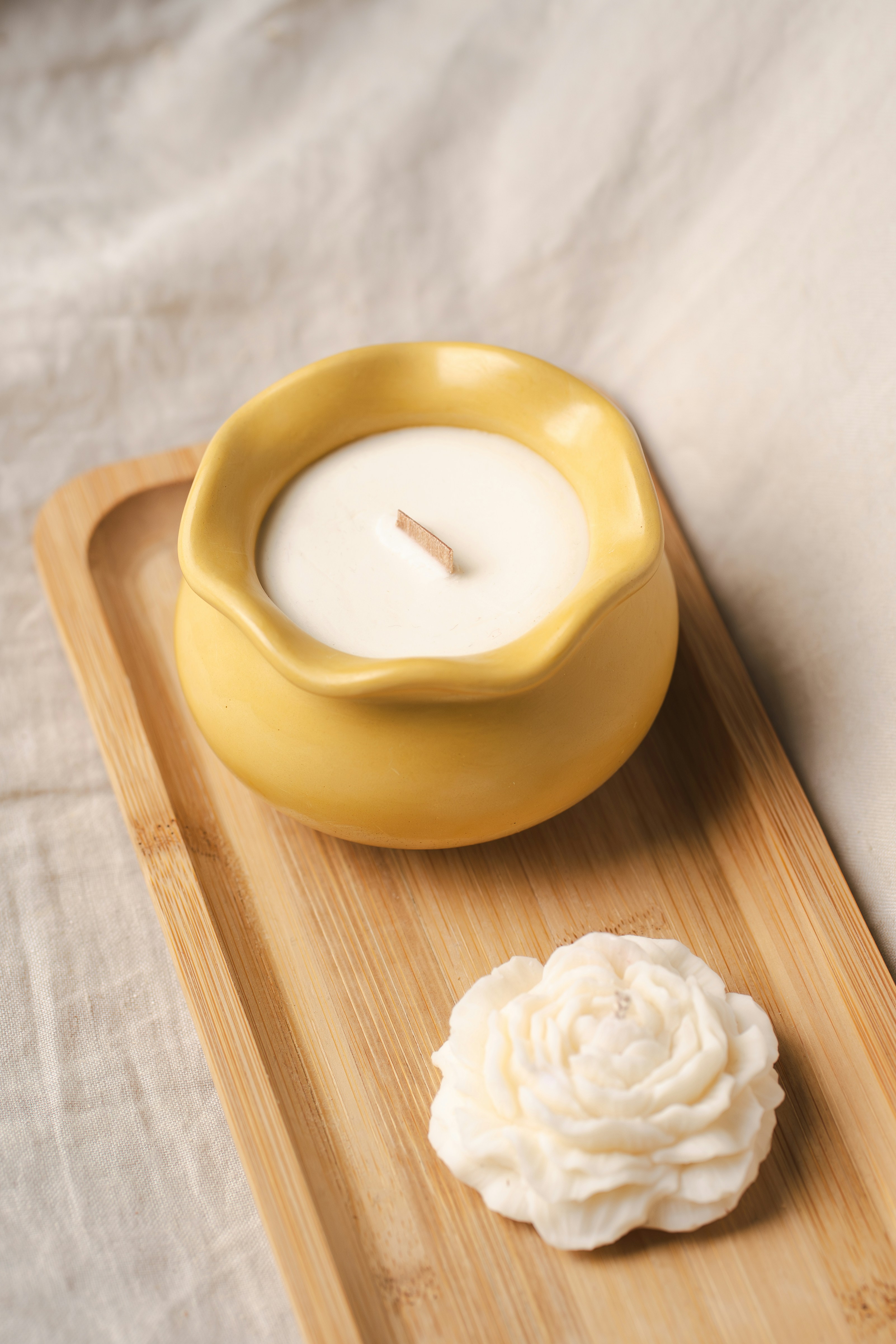 A yellow candle and rose sit on a tray.