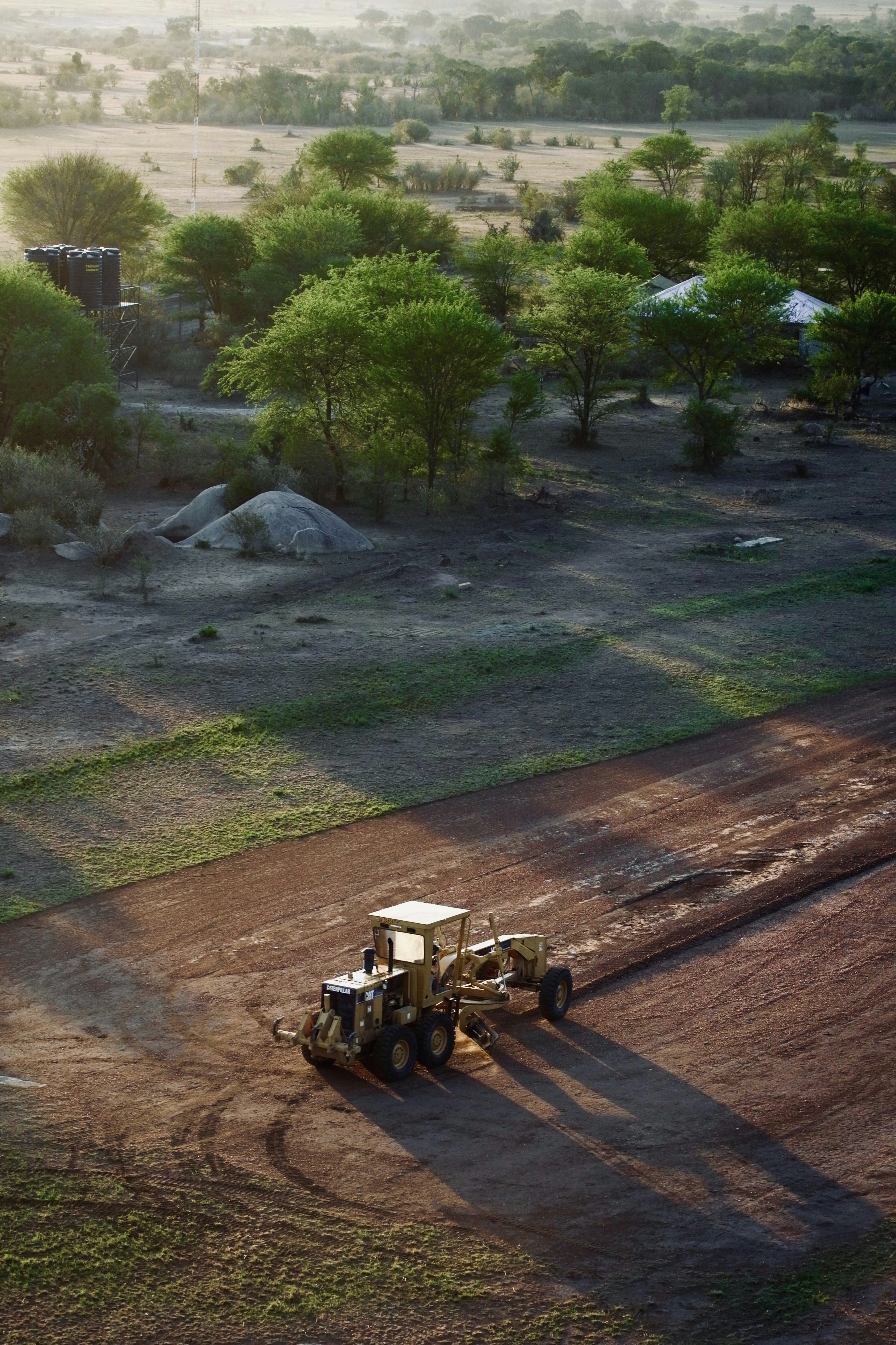 A bulldozer levels land in a rural landscape.