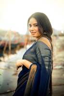 A woman in a saree smiles at the camera.