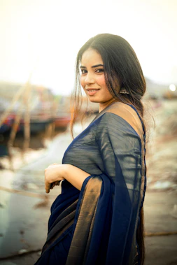 A woman in a saree smiles at the camera.