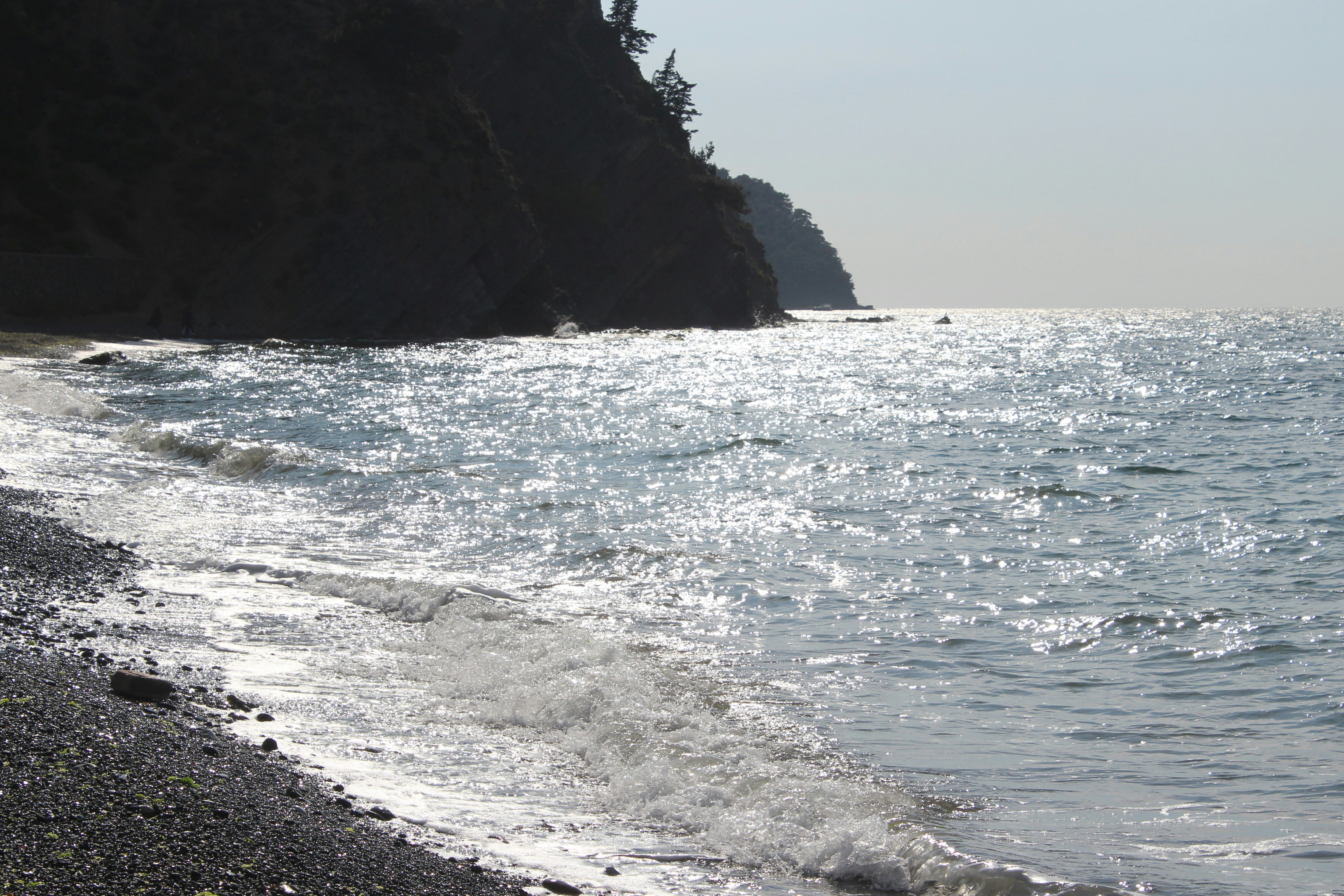 Waves crash onto a rocky beach with cliffs.
