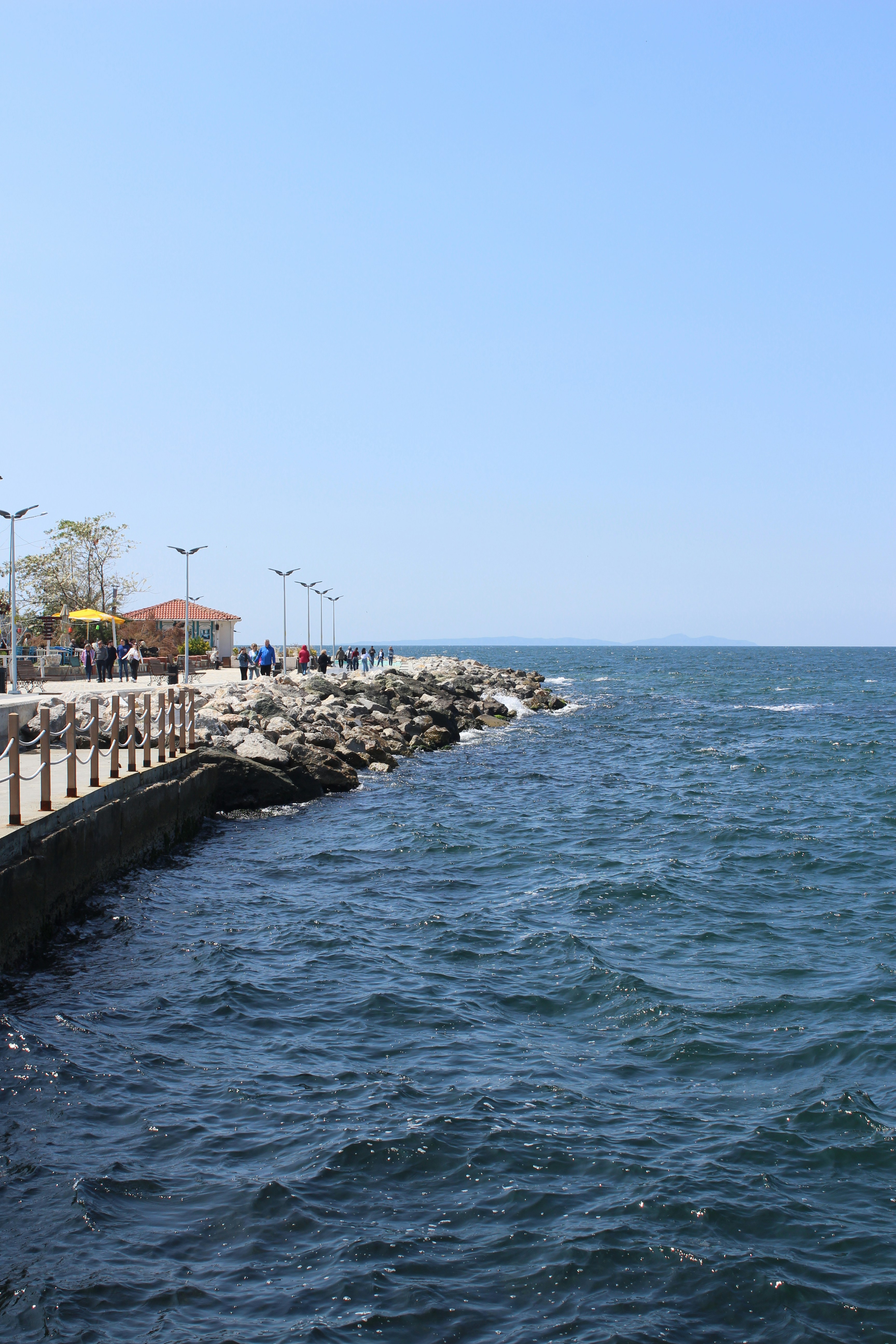 A pier and rocky shoreline meet the ocean.