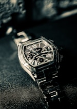 A cartier watch lies on a textured surface.